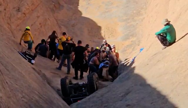 A group forms a chain and carries the hurt man down the slope to the helicopter near Moab on Saturday.