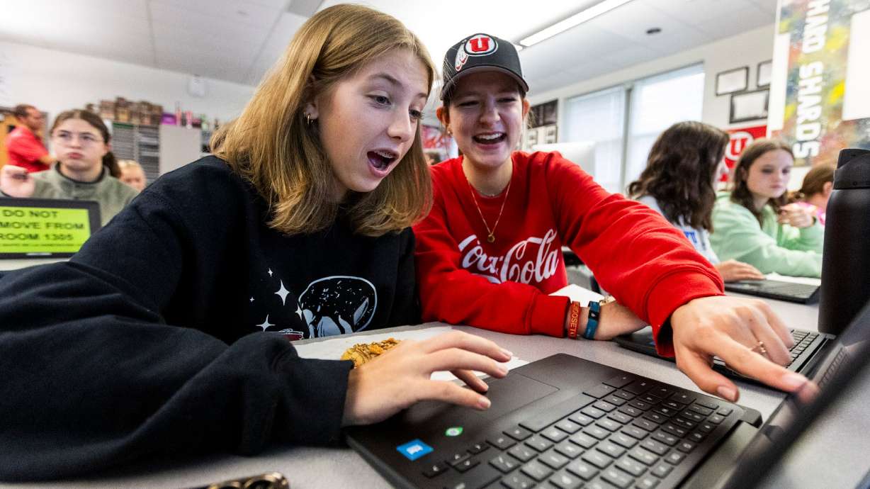 Juniors Natalie Sanford, 17, on the right, and Quincie Starks, 16, laugh with each other while trading simulated stocks on MarketWatch.com, at a meeting of the Girls Investing Club at Herriman High School in Herriman on Oct. 18.