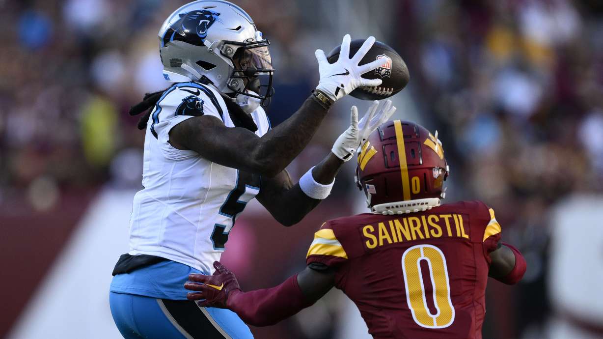 Carolina Panthers wide receiver Diontae Johnson (5) catches a pass over Washington Commanders cornerback Mike Sainristil (0) during the first half of an NFL football game, Sunday, Oct. 20, 2024, in Landover, Md.