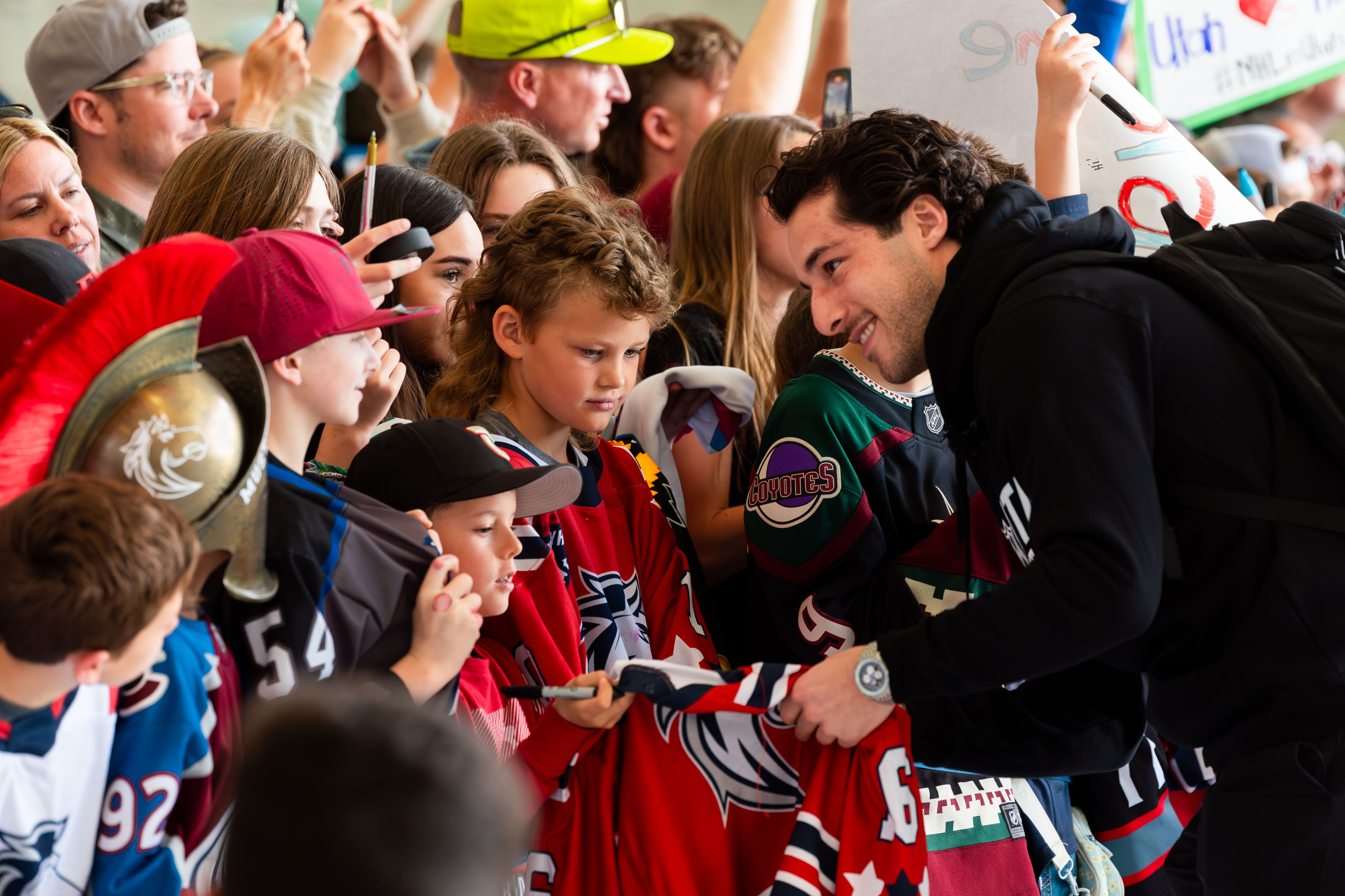 Sean Durzi, member of the new Utah Hockey Club, signs autographs for a crowd made up of youth from local hockey programs that greets the team upon their arrival at Signature Aviation SLC in Salt Lake City on April 24.