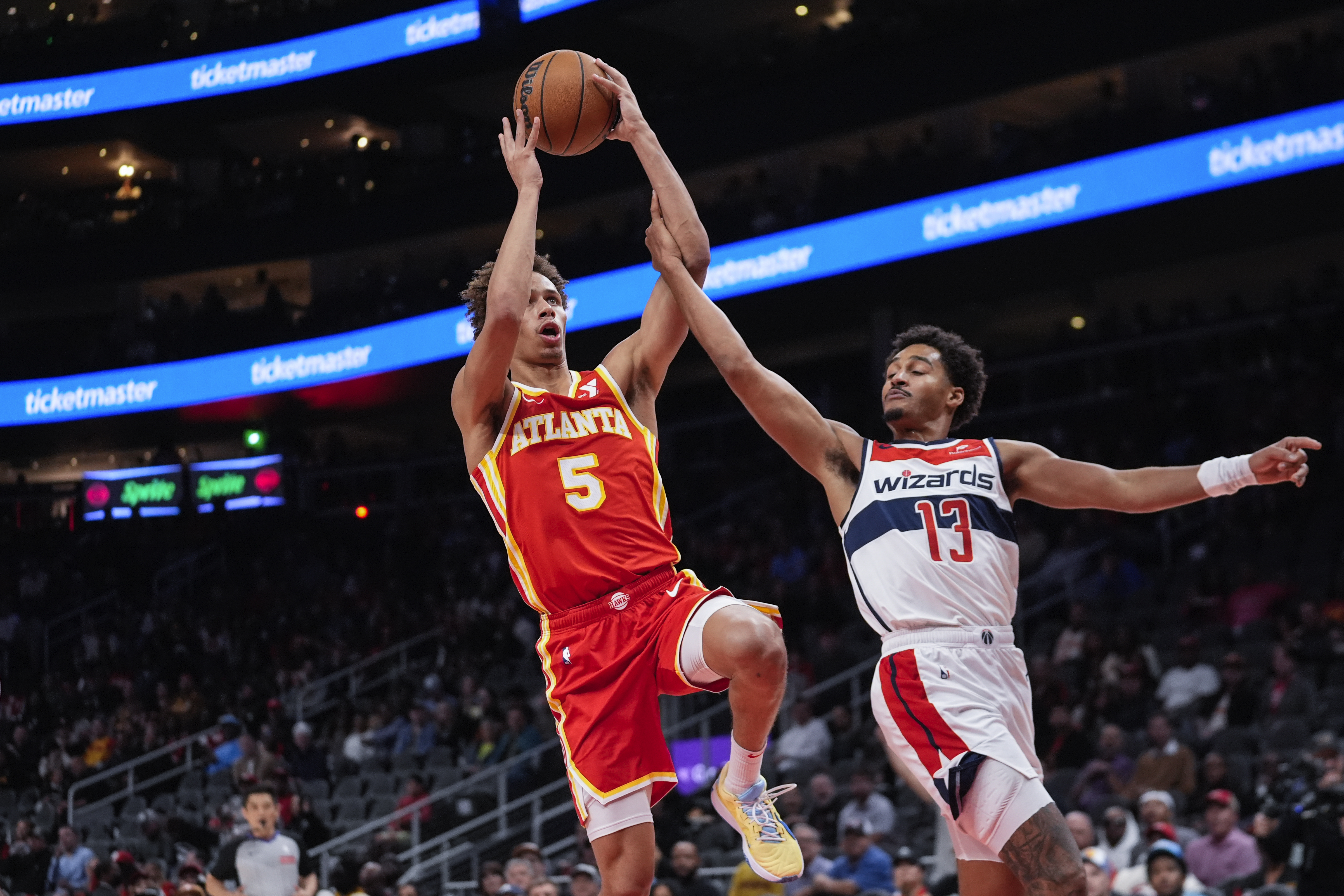 Atlanta Hawks guard Dyson Daniels (5) is fouled by Washington Wizards guard Jordan Poole (13) as he drives to the basket during the first half of an NBA basketball game Monday, Oct. 28, 2024, in Atlanta.