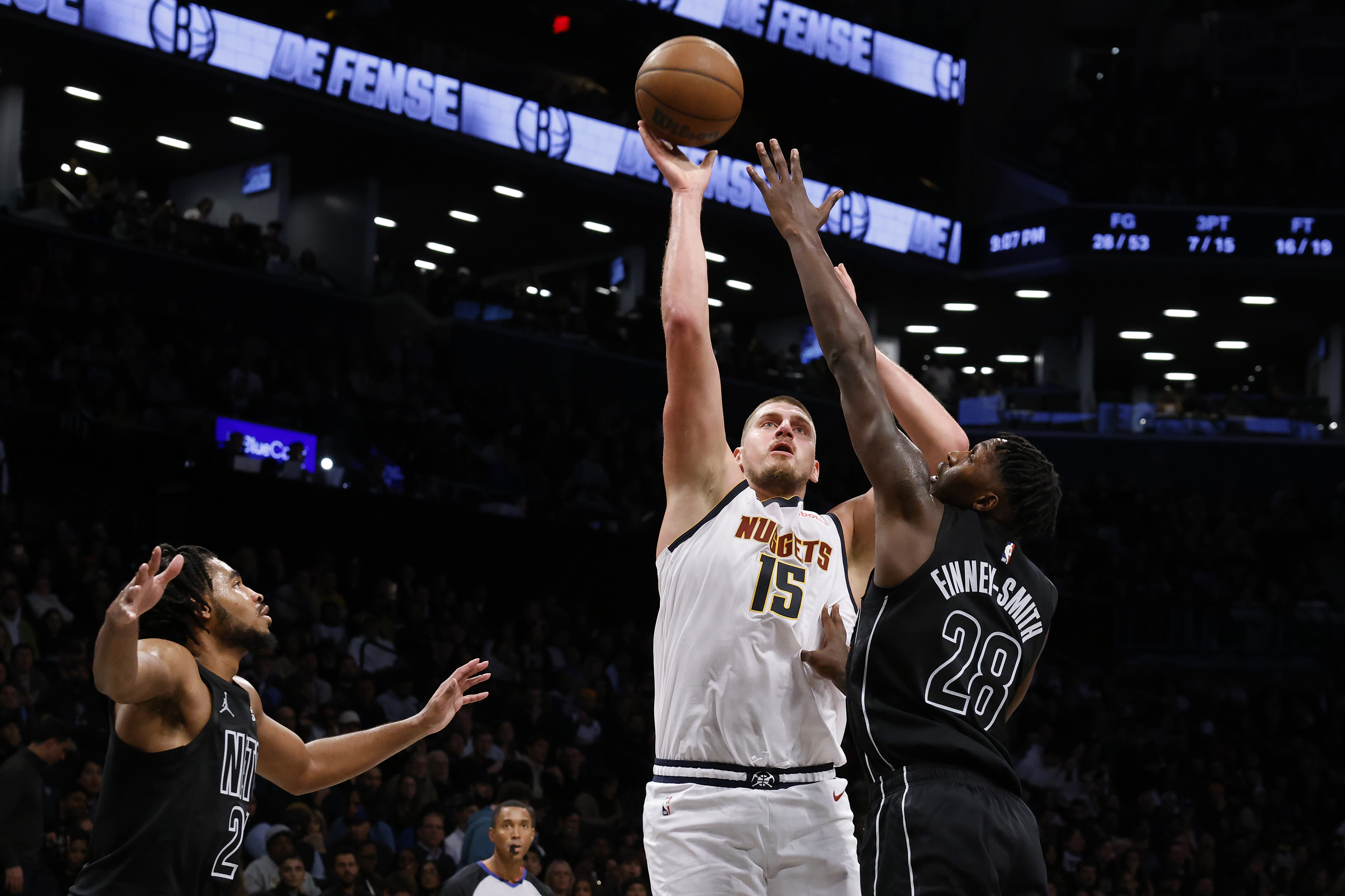 Denver Nuggets' Nikola Jokic (15), of Serbia, shoots against Brooklyn Nets' Dorian Finney-Smith (28) and Cam Thomas, left, during the third quarter of an NBA basketball game Tuesday, Oct. 29, 2024, in New York.