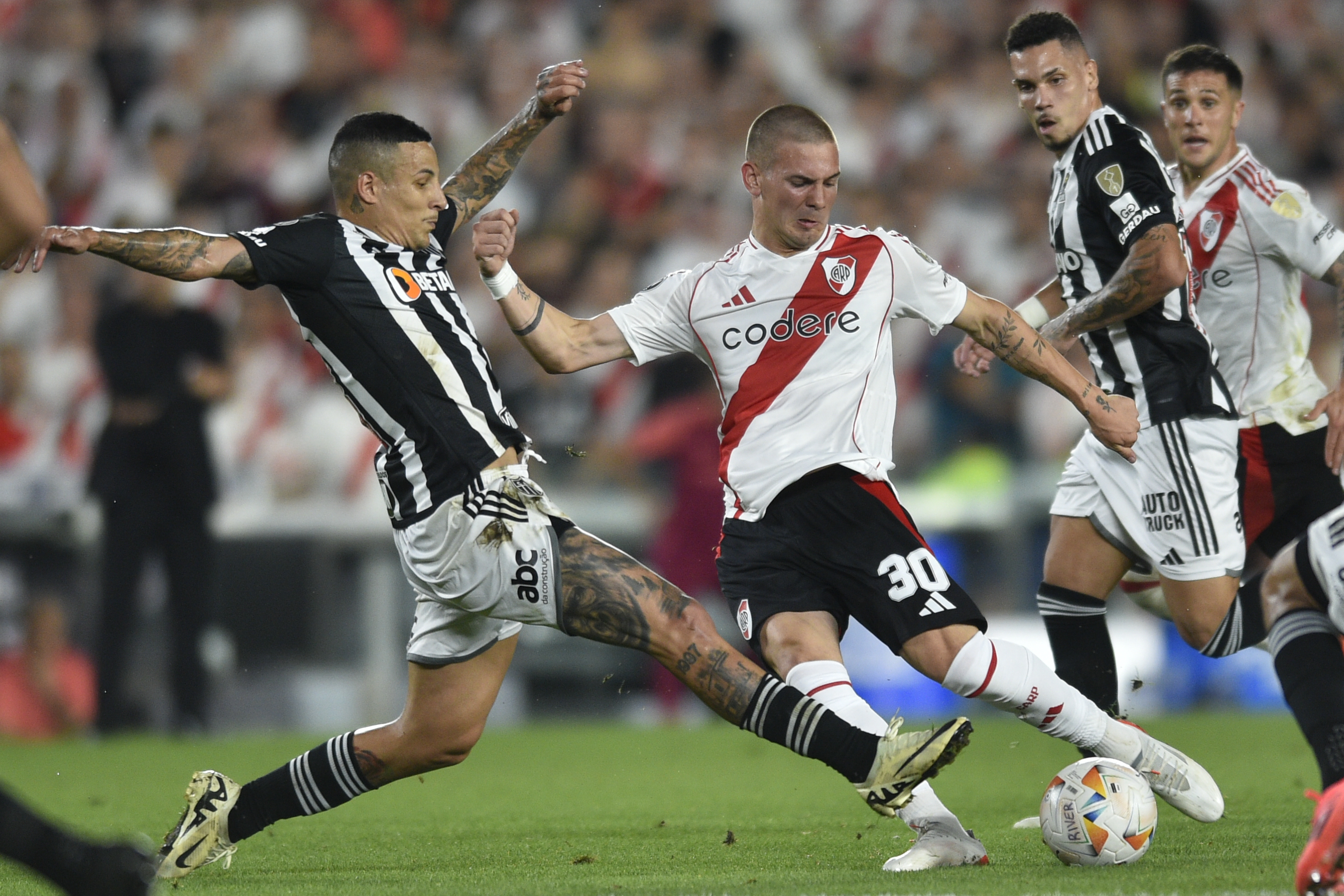 Franco Mastantuono of Argentina's River Plate, center, and Junior Alonso of Brazil's Atletico Mineiro battle for the ball during a Copa Libertadores semifinal second leg soccer match at Monumental stadium in Buenos Aires, Argentina, Tuesday, Oct. 29, 2024.