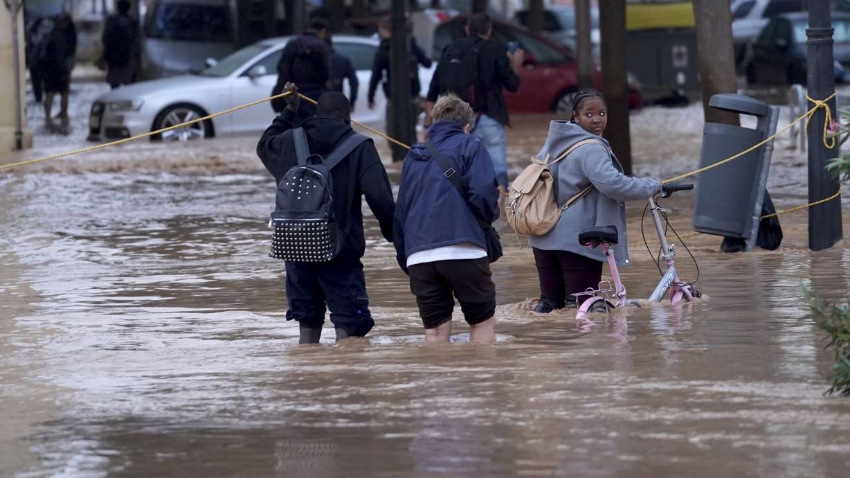 People walk through flooded streets in Valencia, Wednesday. Authorities say flash floods in Spain turned village streets into rivers, ruined homes, disrupted transportation and killed at least 95 people.