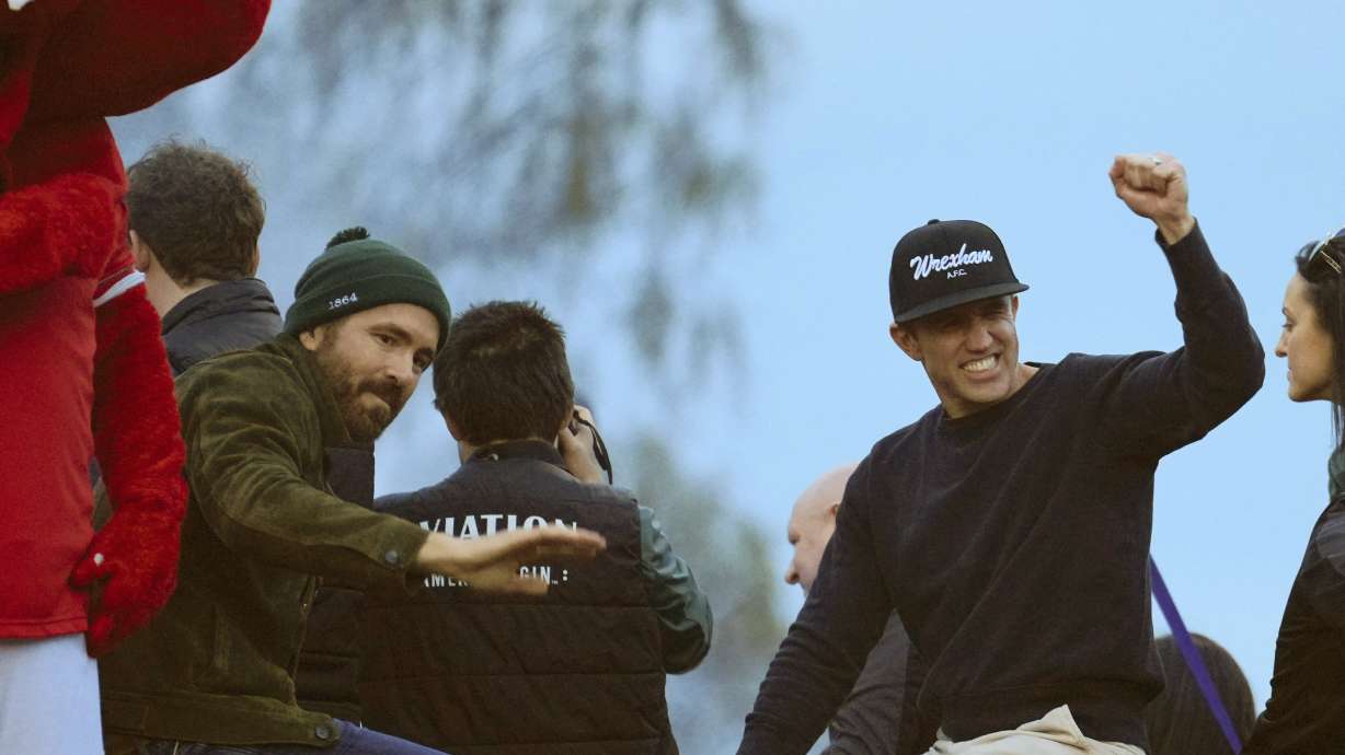 FILE - Wrexham co-owners Ryan Reynolds, left, and Rob McElhenney, right, celebrate their team's promotion to the Football League in Wrexham, Wales, Tuesday, May 2, 2023.