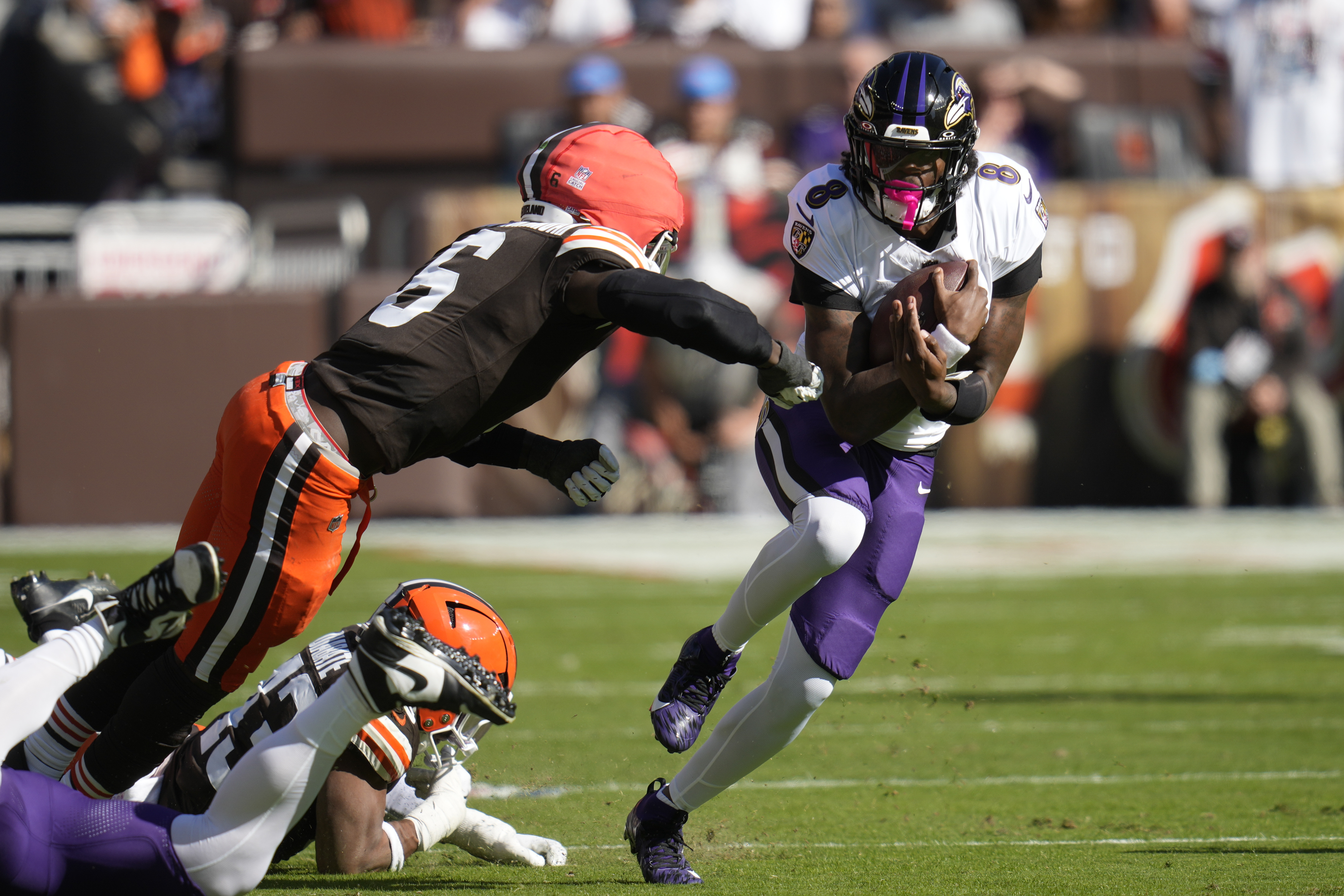 Baltimore Ravens quarterback Lamar Jackson (8) cuts past Cleveland Browns linebacker Jeremiah Owusu-Koramoah (6)\ during the first half of an NFL football game in Cleveland, Sunday, Oct. 27, 2024. 