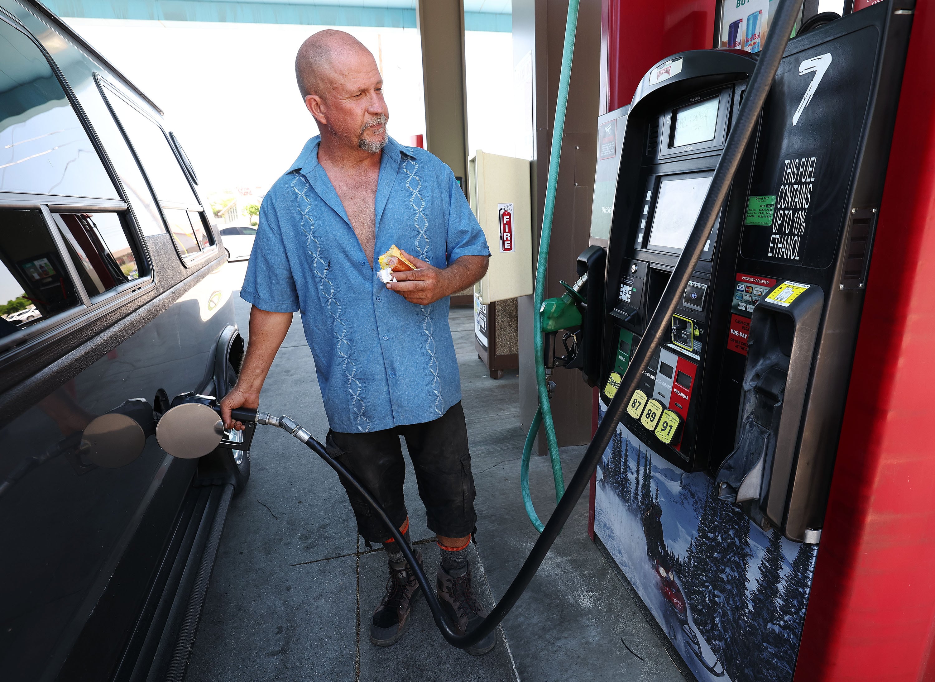 Mike Nelson fills his tank in Midvale on June 11. Petroleum industry watchers report U.S. gas prices continued to decline this week, reaching a median price of $2.99 per gallon even as military conflict in and around Middle East oil-producing nations continues.