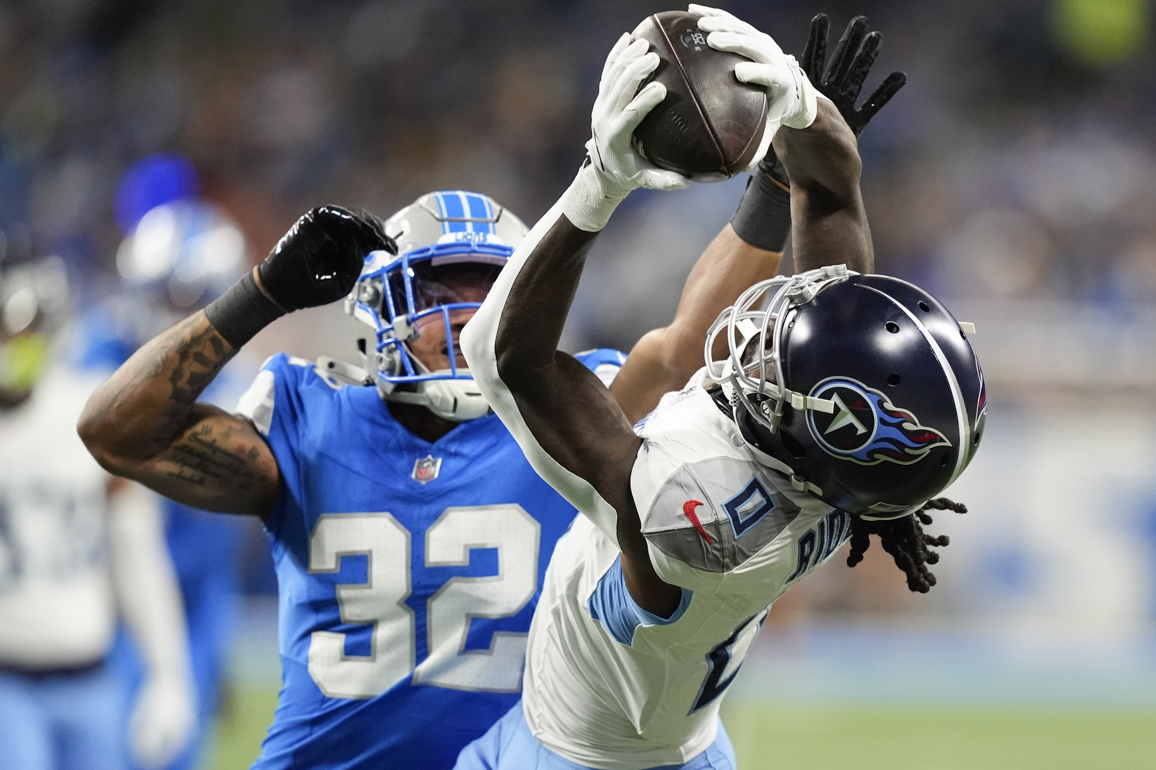 Tennessee Titans wide receiver Calvin Ridley (0) makes a catch past Detroit Lions safety Brian Branch (32) during the first half of an NFL football game Sunday, Oct. 27, 2024, in Detroit.