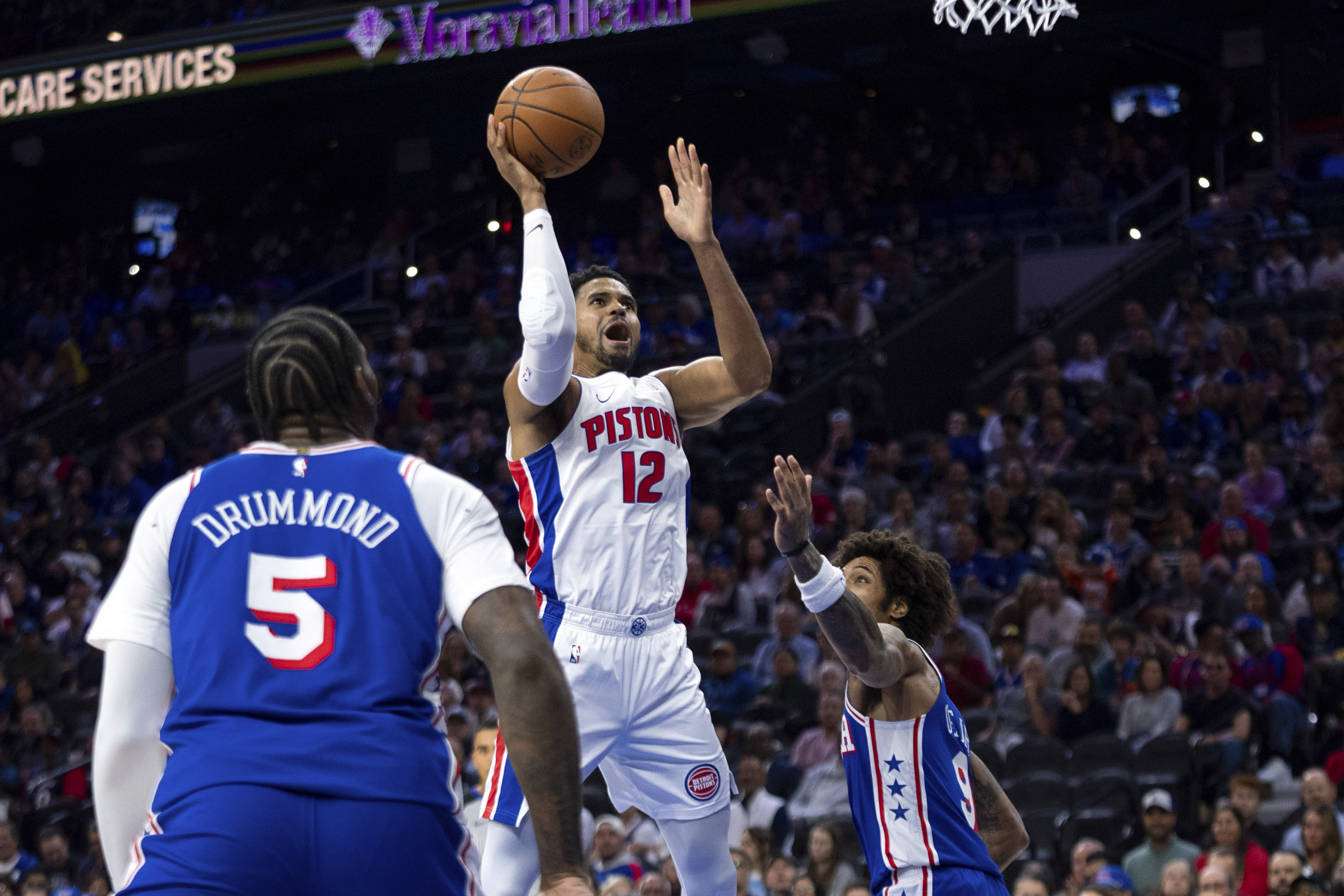 Detroit Pistons' Tobias Harris, center, shoots the ball with Philadelphia 76ers' Andre Drummond, left, and Kelly Oubre Jr., right, defending during the first half of an NBA basketball game, Wednesday, Oct. 30, 2024, in Philadelphia.