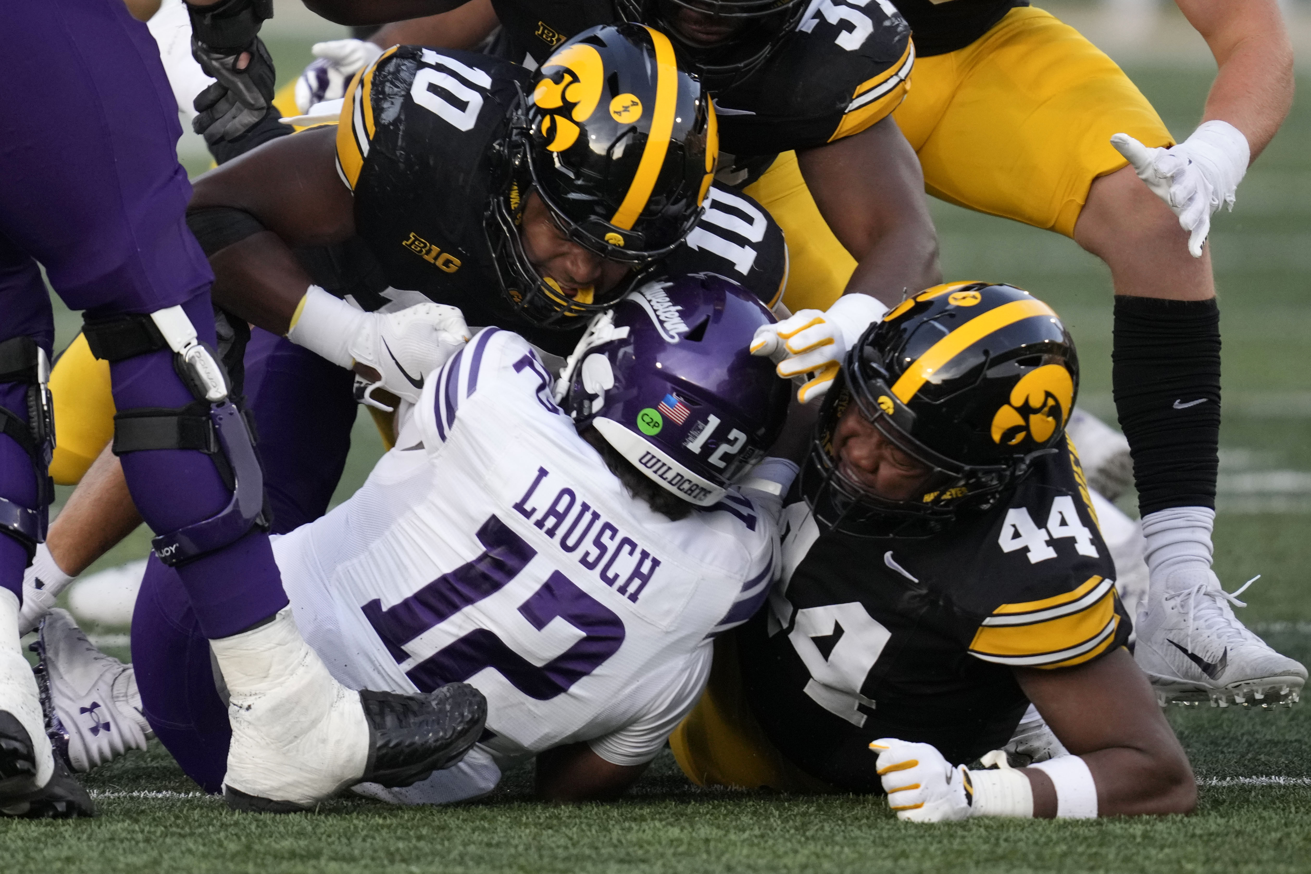 Northwestern quarterback Jack Lausch (12) is sacked by Iowa linebacker Nick Jackson (10) and defensive lineman Kenneth Merrieweather (44) during the second half of an NCAA college football game, Saturday, Oct. 26, 2024, in Iowa City, Iowa. Iowa won 40-14.