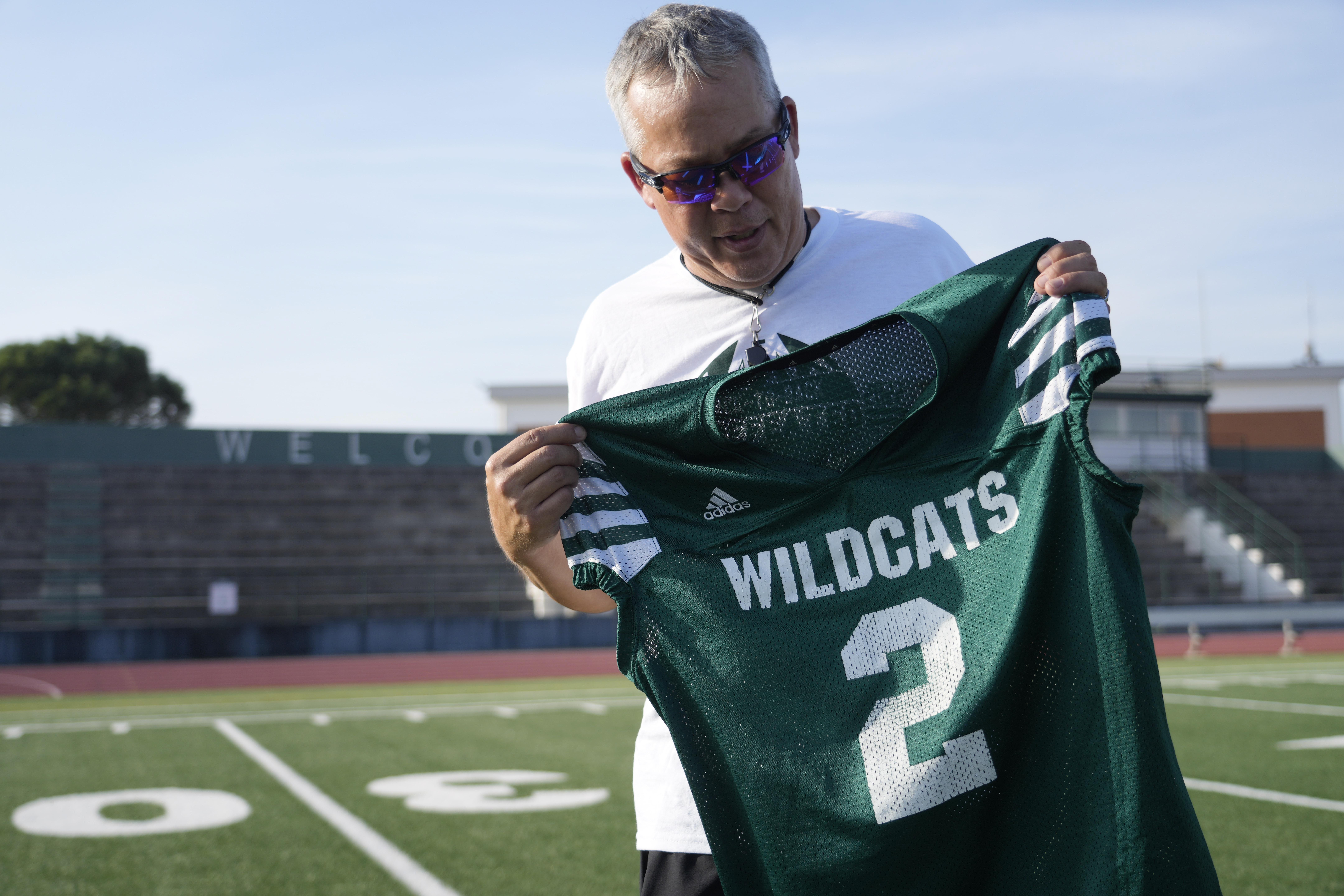 Coach Jim Davis shows the jersey worn by Ashton Jeanty as he is interviewed by The Associated Press prior to the start of a training session at the football field of the U.S. Naval Support – Site in Gricignano di Aversa, southern Italy, Tuesday, Oct. 29, 2024. 