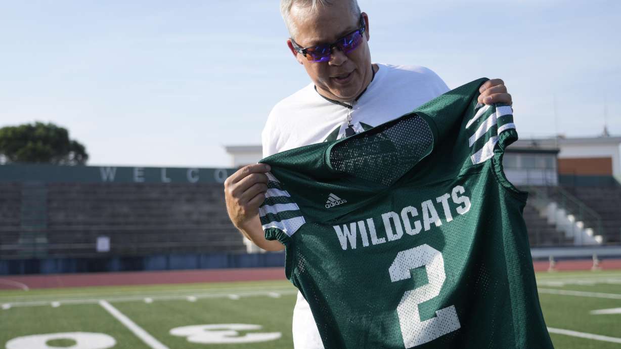 Coach Jim Davis shows the jersey worn by Ashton Jeanty as he is interviewed by The Associated Press prior to the start of a training session at the football field of the U.S. Naval Support – Site in Gricignano di Aversa, southern Italy, Tuesday, Oct. 29, 2024.