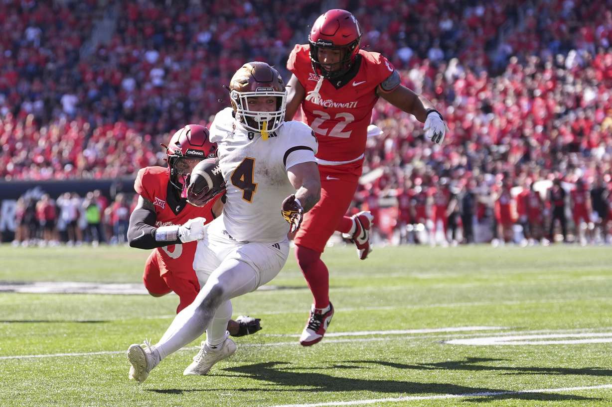 Arizona State's Cam Skattebo breaks a tackle by Cincinnati's Josh Minkins on a touchdown run during the second half of an NCAA college football game, Saturday, Oct. 19, 2024, in Cincinnati.