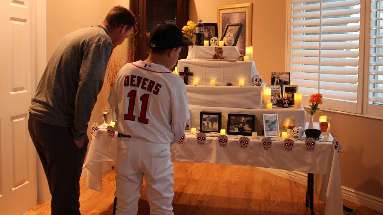 Areli Olsen's husband John Olsen and their son Lucas inspect the ofrenda at their South Jordan home on Thursday. Areli Olsen started the tradition of installing an ofrenda in the family's home to mark Día de los Muertos each year.