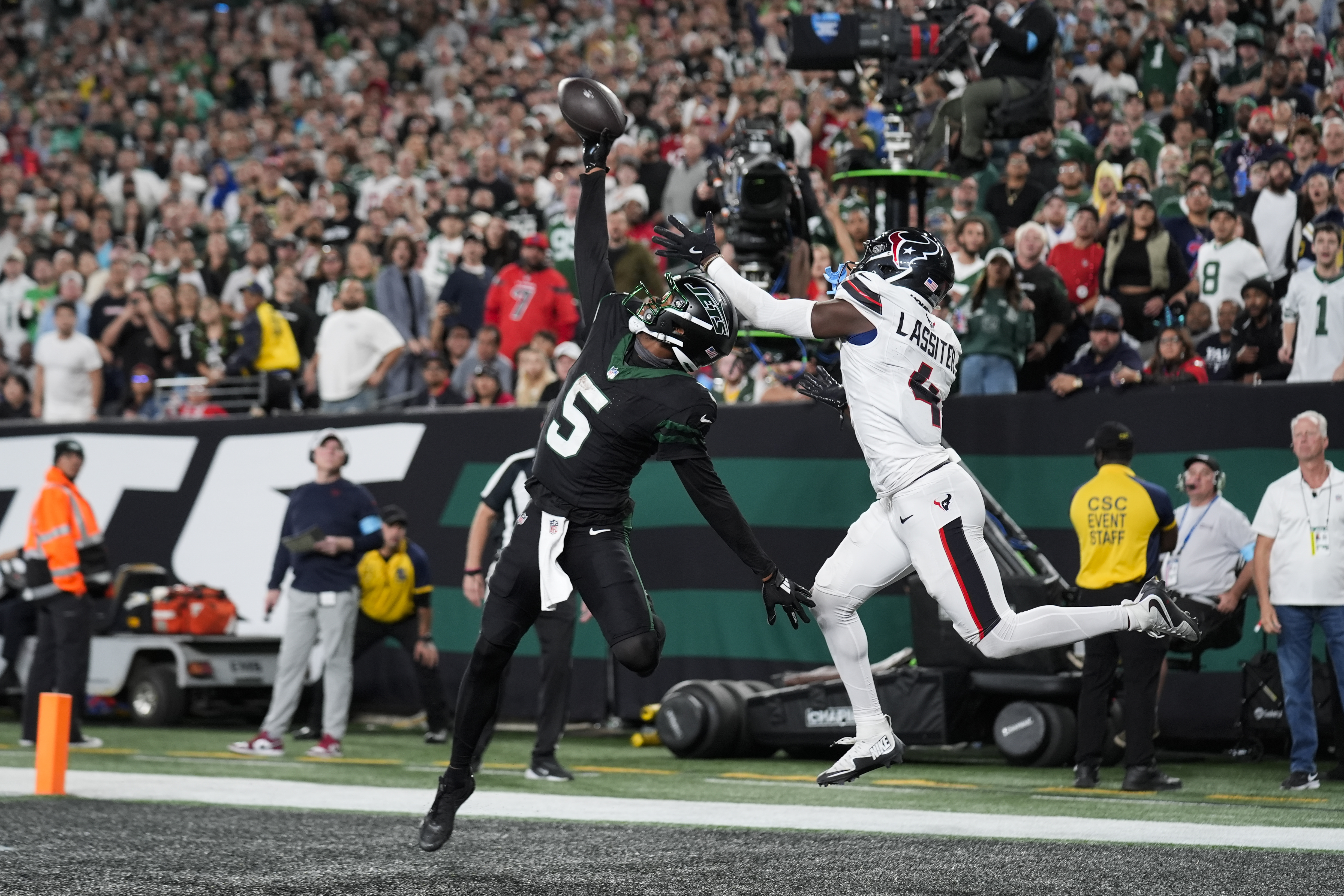 New York Jets wide receiver Garrett Wilson (5) catches a pass for a touchdown as Houston Texans cornerback Kamari Lassiter (4) defends during the second half of an NFL football game Thursday, Oct. 31, 2024, in East Rutherford, N.J.
