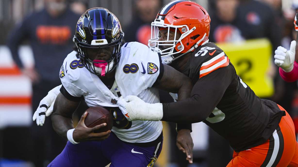 Cleveland Browns defensive end Za'Darius Smith (99) sacks Baltimore Ravens quarterback Lamar Jackson (8) during the second half of an NFL football game in Cleveland, Sunday, Oct. 27, 2024.