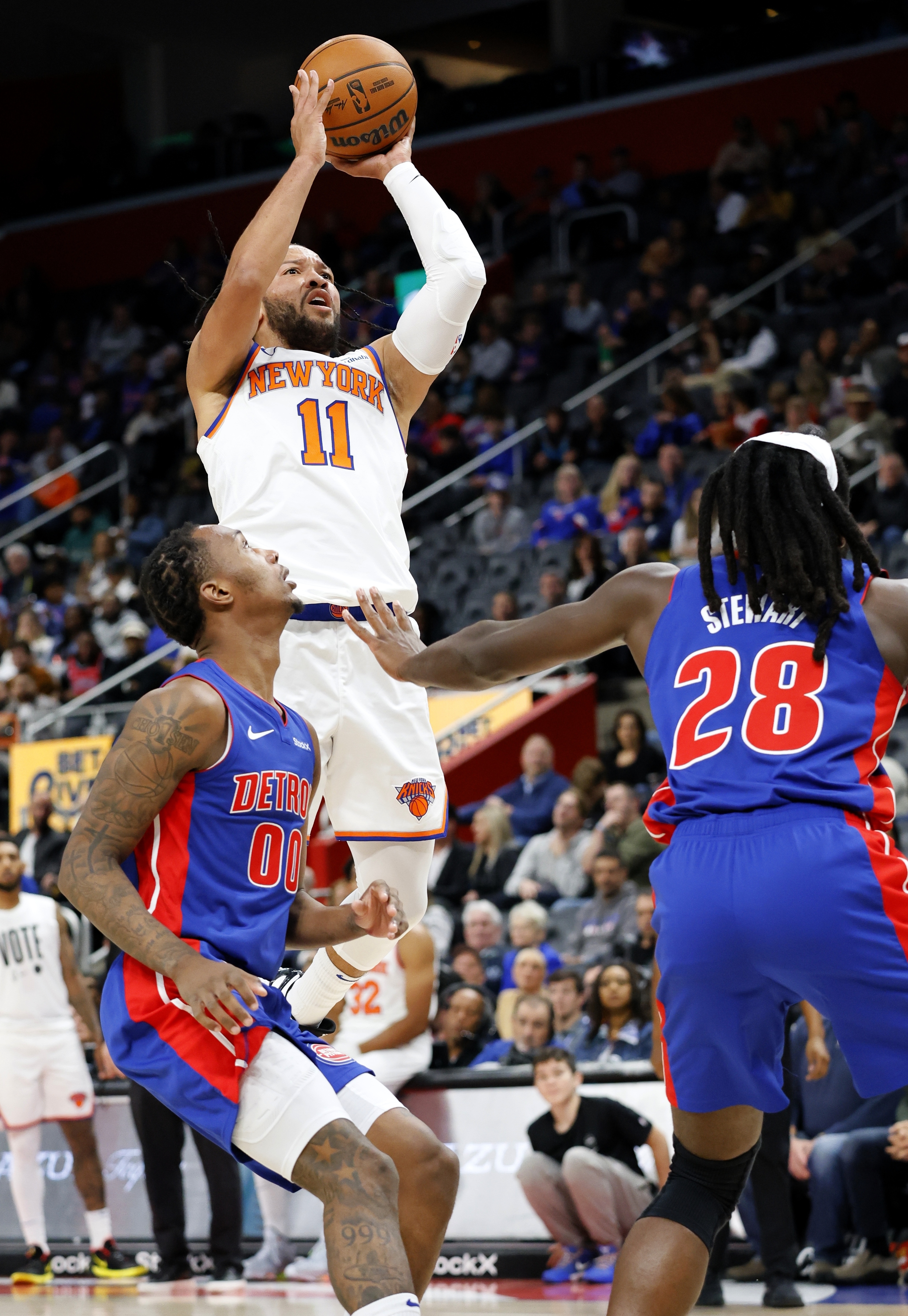 New York Knicks guard Jalen Brunson (11) takes a shot against Detroit Pistons forward Ronald Holland II (00) and center Isaiah Stewart (28) during the first half of an NBA basketball game, Friday, Nov. 1, 2024, in Detroit.