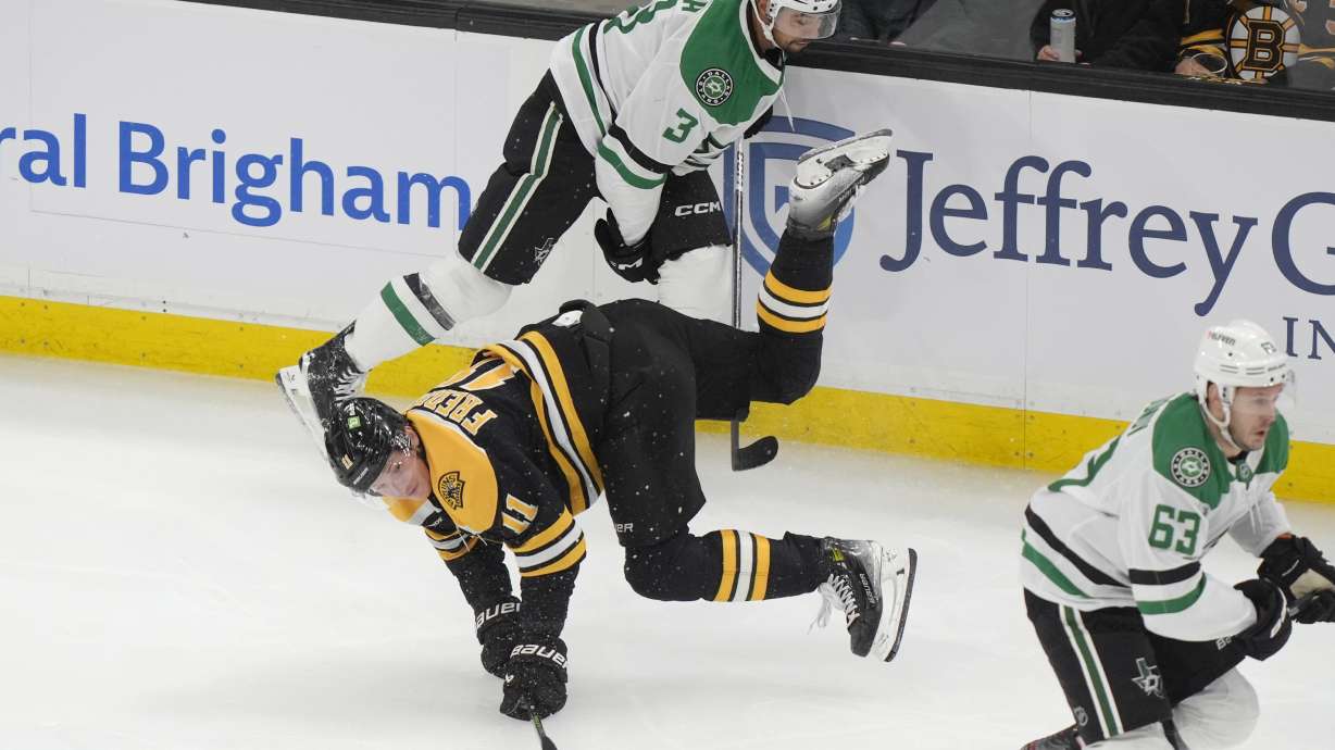 Boston Bruins center Trent Frederic (11) hits the ice as Dallas Stars defenseman Mathew Dumba (3) and right wing Evgenii Dadonov (63) vie for position in the first period of an NHL hockey game, Thursday, Oct. 24, 2024, in Boston.