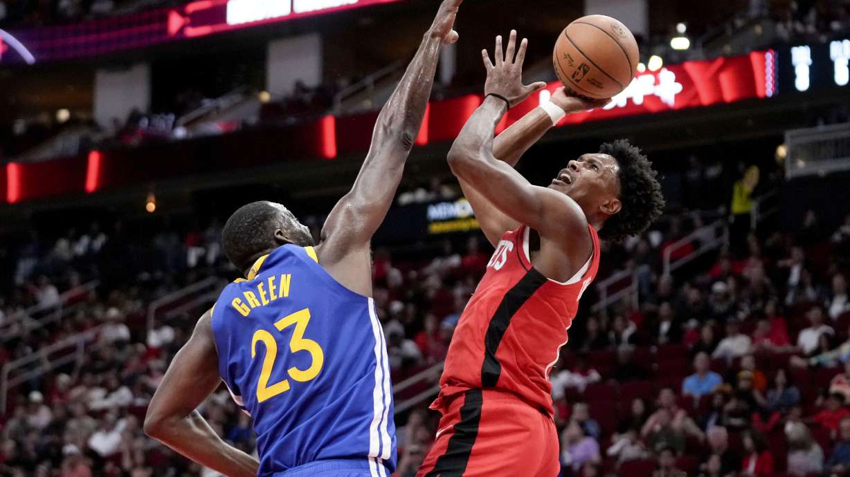 Houston Rockets forward Amen Thompson, right, shoots as Golden State Warriors forward Draymond Green defends during the first half of an NBA basketball game Saturday Nov. 2, 2024, in Houston.