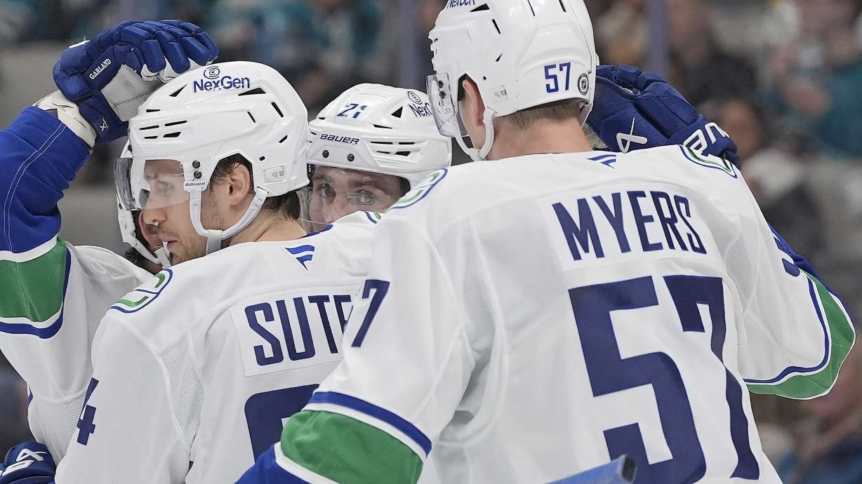 Vancouver Canucks center Pius Suter (24) is congratulated by defenseman Tyler Myers (57) and teammates after scoring a goal against the San Jose Sharks during the second period of an NHL hockey game in San Jose, Calif., Saturday, Nov. 2, 2024.
