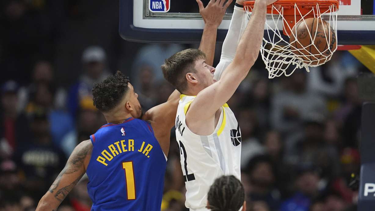 Utah Jazz forward Kyle Filipowski, right, dunks the ball for a basket as Denver Nuggets forward Michael Porter Jr. defends in the first half of an NBA basketball game Saturday, Nov. 2, 2024, in Denver.