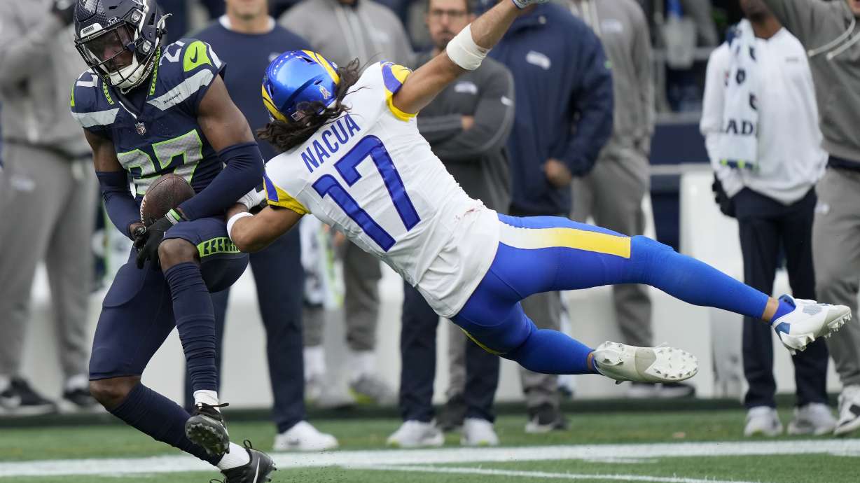 Seattle Seahawks cornerback Riq Woolen, left, intercepts a pass intended for Los Angeles Rams wide receiver Puka Nacua (17) during the first half of an NFL football game in Seattle, Sunday, Nov. 3, 2024.