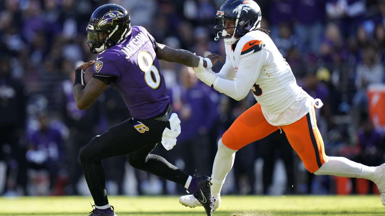 Baltimore Ravens quarterback Lamar Jackson, left, is pursued by Denver Broncos linebacker Baron Browning in the first half of an NFL football game Sunday, Nov. 3, 2024, in Baltimore.