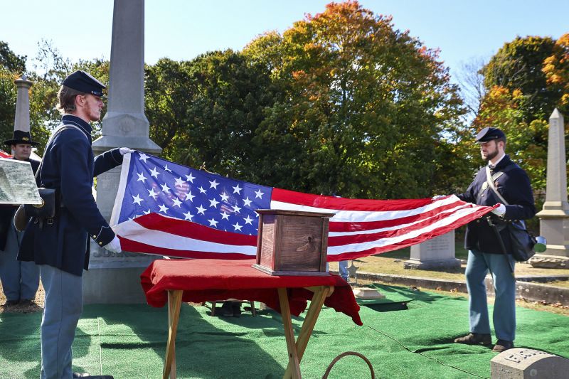 Civil War reenactors fold an American flag near an urn, center, containing the cremated remains of Byron R. Johnson, a Union soldier who was born in Pawtucket, Rhode Island, in 1844, and buried in the same city Oct. 16 this year.