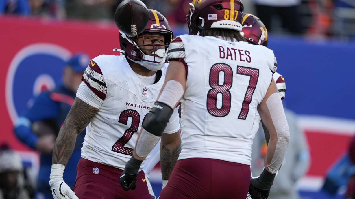 Washington Commanders running back Chris Rodriguez Jr. (23) celebrates with tight end John Bates (87) after gaining a first down against the New York Giants during the fourth quarter of an NFL football game, Sunday, Nov. 3, 2024, in East Rutherford, N.J.