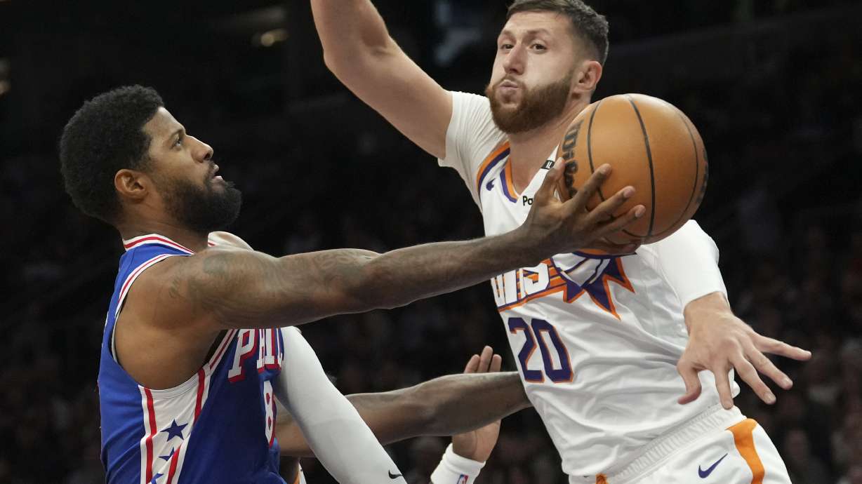 Philadelphia 76ers forward Paul George, left, drives to the basket against Phoenix Suns center Jusuf Nurkic (20) during the first half of an NBA basketball game Monday, Nov. 4, 2024, in Phoenix.