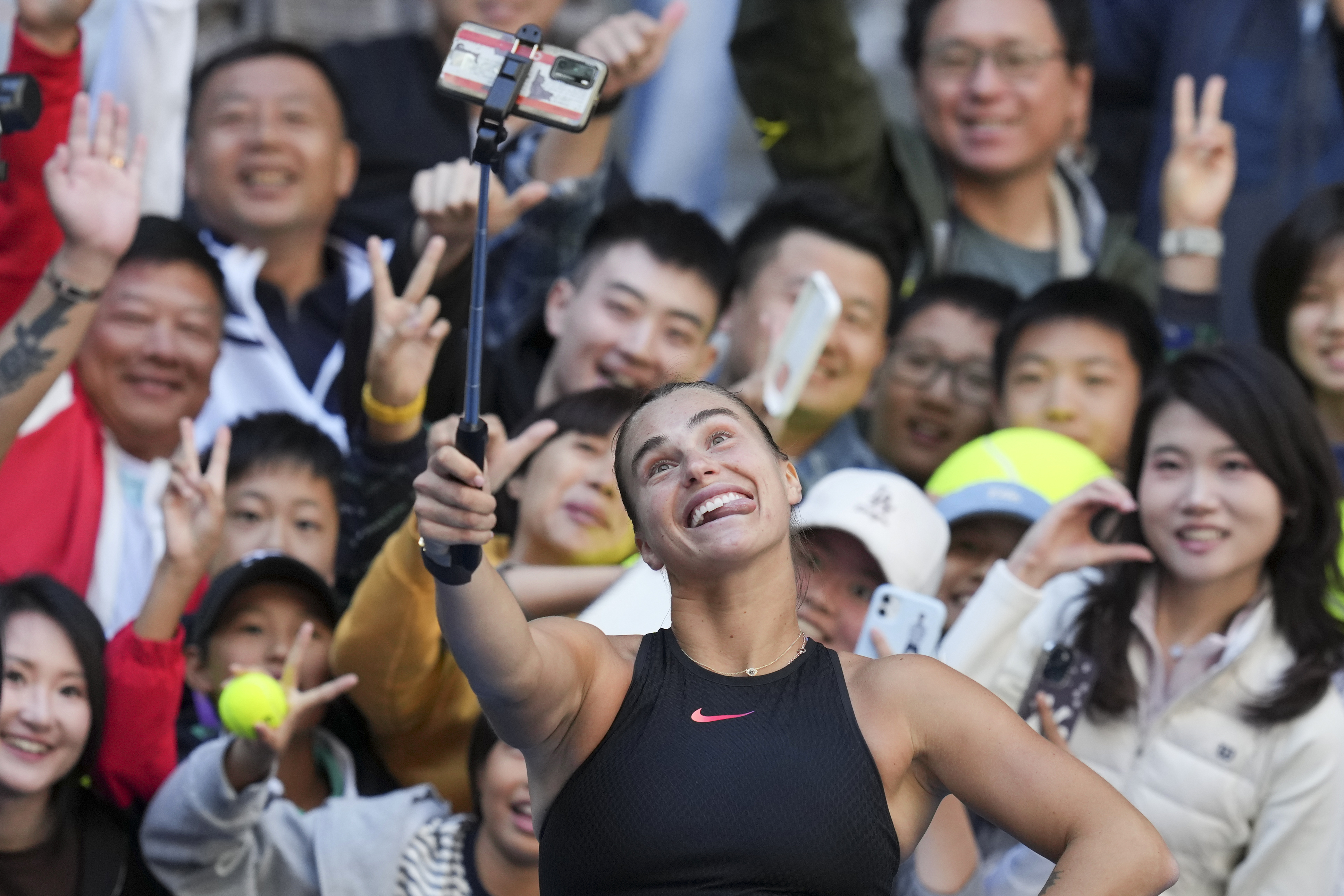 Aryna Sabalenka of Belarus takes a selfie with fans after winning against Madison Keys of the United States during their women's singles match of the China Open tennis tournament, at the National Tennis Center in Beijing, Wednesday, Oct. 2, 2024.