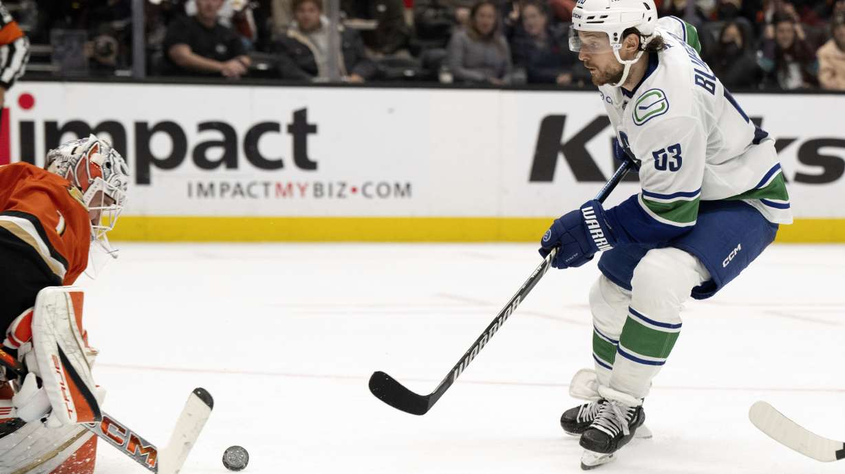 Vancouver Canucks center Teddy Blueger, right, takes a shot against Anaheim Ducks goaltender Lukas Dostal (1) during the second period of an NHL hockey game in Anaheim, Calif., Tuesday, Nov. 5, 2024.