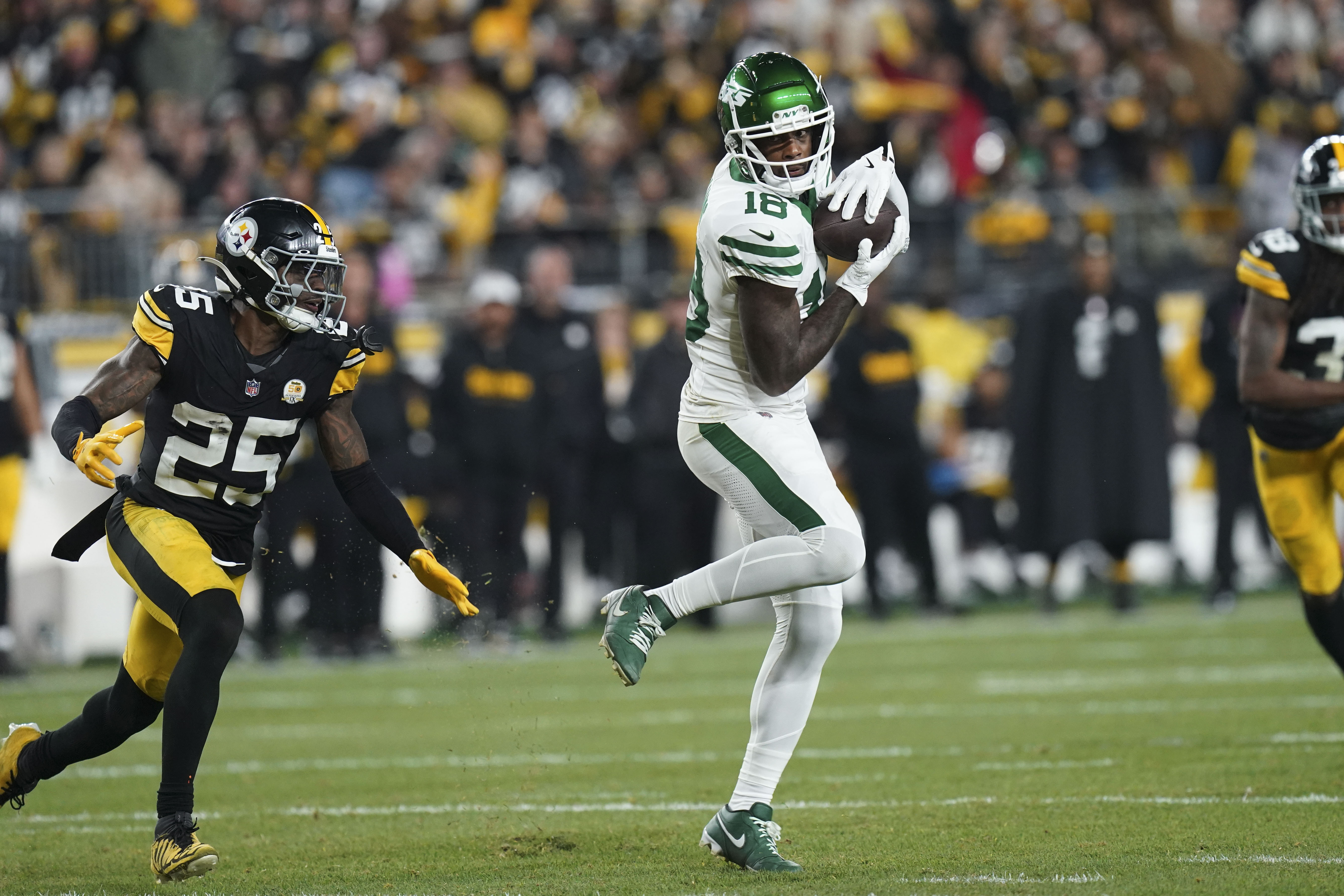 New York Jets wide receiver Mike Williams (18) pulls in a pass against Pittsburgh Steelers safety DeShon Elliott (25) in the second half of an NFL football game in Pittsburgh, Sunday, Oct. 20, 2024.