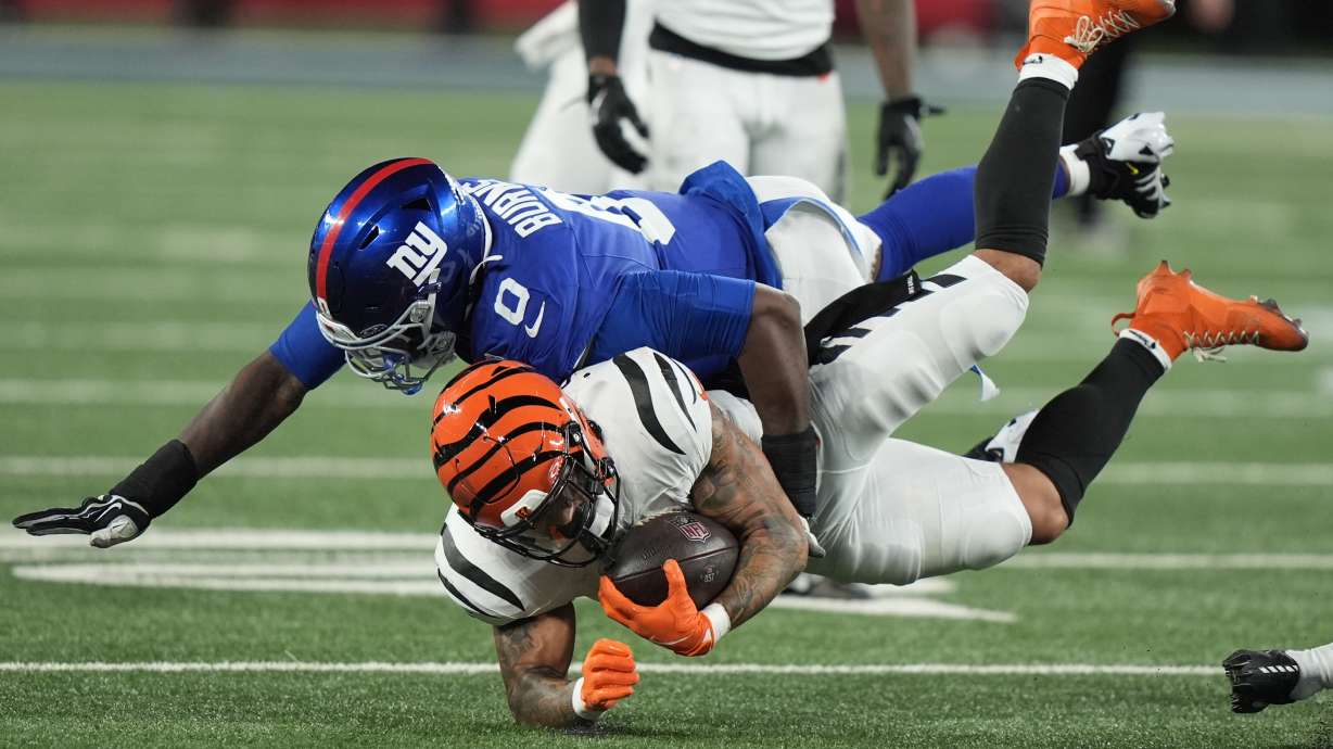 New York Giants linebacker Brian Burns (0) tackles Cincinnati Bengals running back Chase Brown during the second half of an NFL football game, Sunday, Oct. 13, 2024, in East Rutherford, N.J.