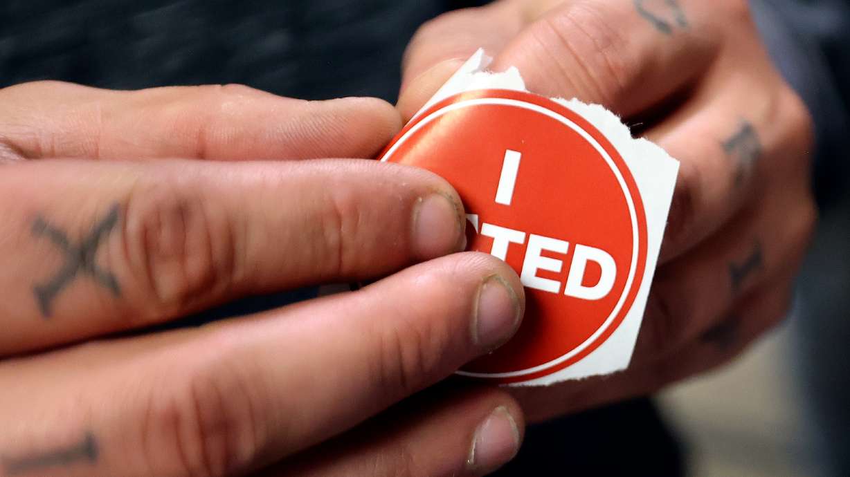 Chris Shibao puts his sticker on after voting at the Salt Lake County Government Center in Salt Lake City on Tuesday.
