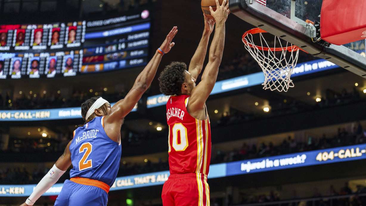 Atlanta Hawks forward Zaccharie Risacher (10) goes up for a slam dunk while guarded by New York Knicks guard Miles McBride (2) during the first half of an NBA basketball game, Wednesday, Nov. 6, 2024, in Atlanta.