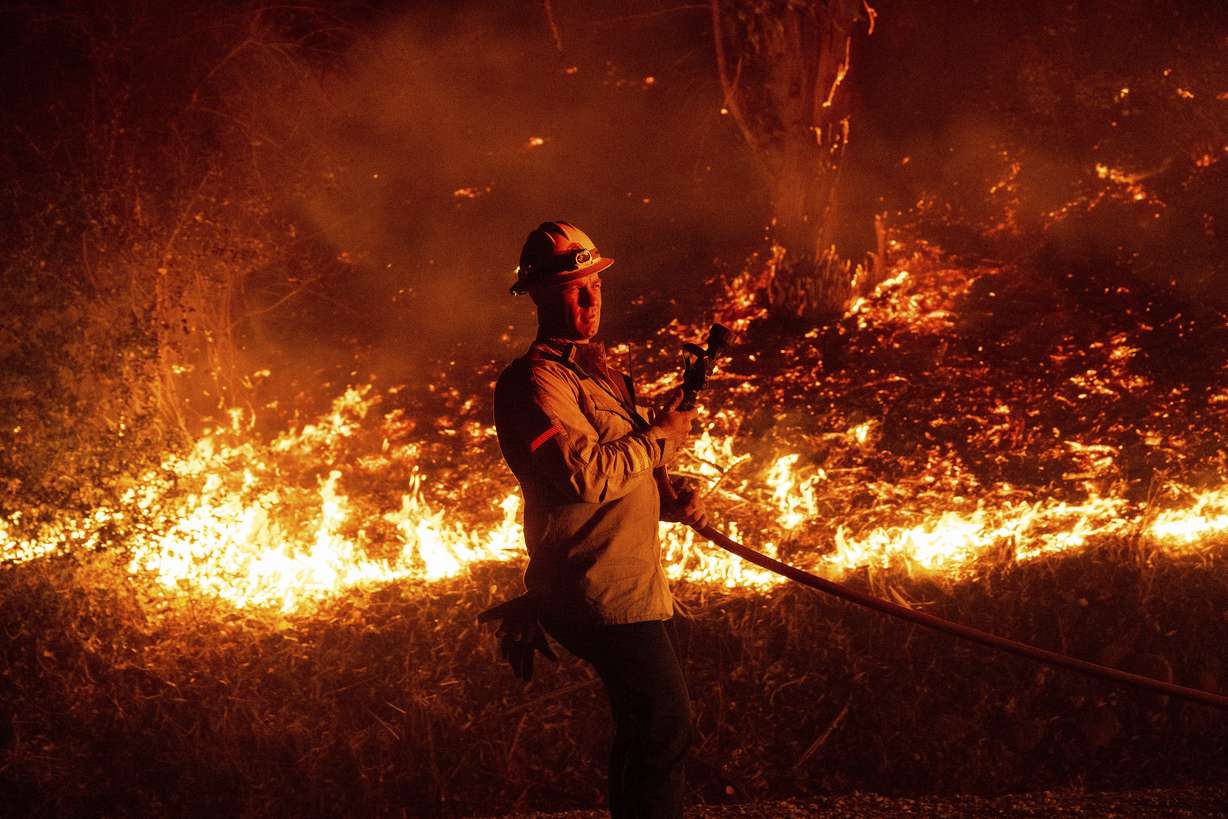 A firefighter prepares to douse flames while battling the Mountain Fire on Wednesday, in Santa Paula, Calif.