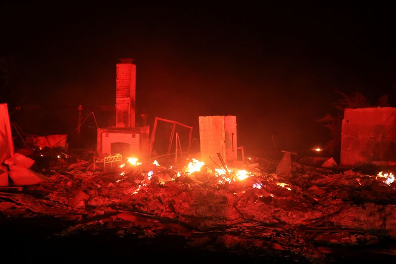 Flames rise from damaged property, as smoke billows from the Mountain Fire in Camarillo, Calif., Wednesday.