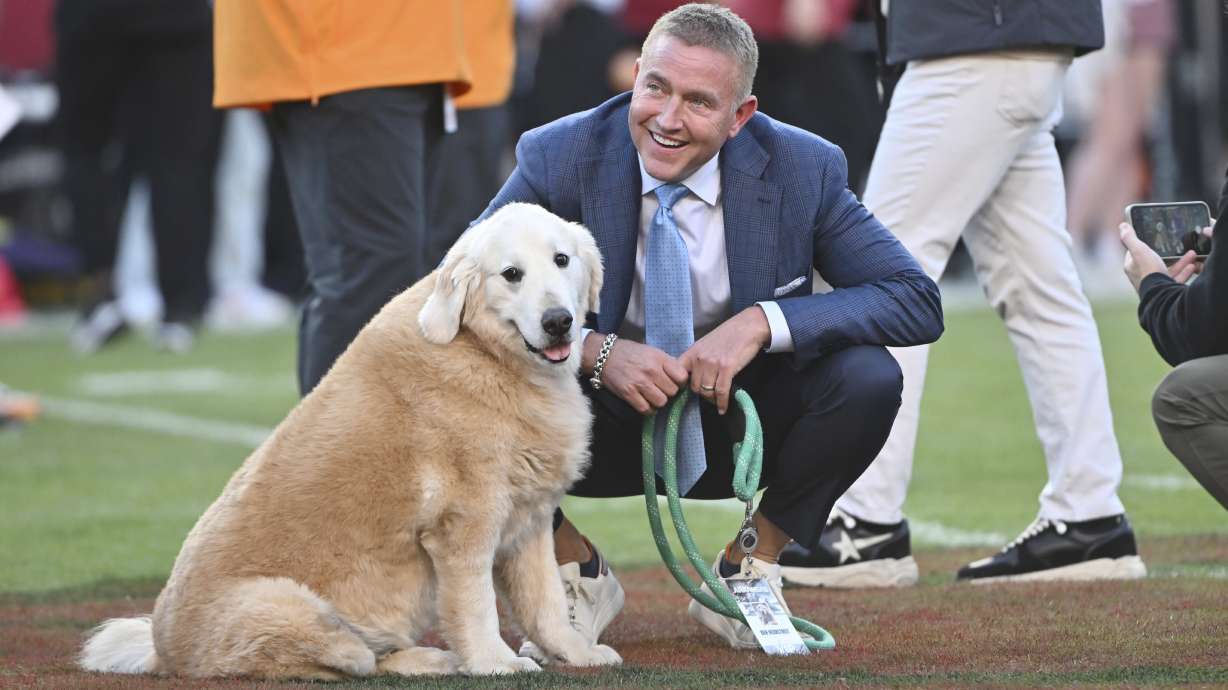 FILE - ESPN's Kirk Herbstreit and his dog Ben watch players warm up before the start of an NCAA college football game between Tennessee and Arkansas, Saturday, Oct. 5, 2024, in Fayetteville, Ark.