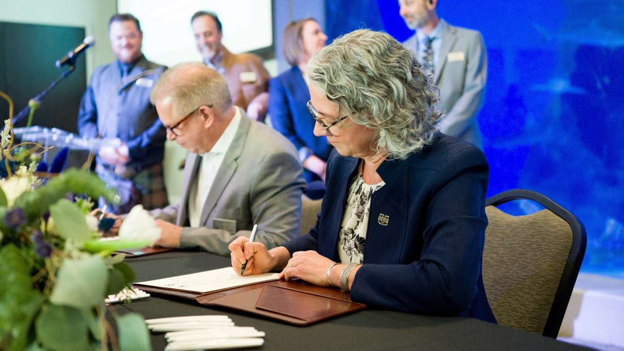 Utah State University Dean Linda Nagel and Loveland Living Planet Aquarium founder and CEO Brent Anderson sign a partnership between the two organizations in Draper on Oct. 25.. USU students can now earn a marine science minor that is already drawing broad interest across the arid Beehive State.