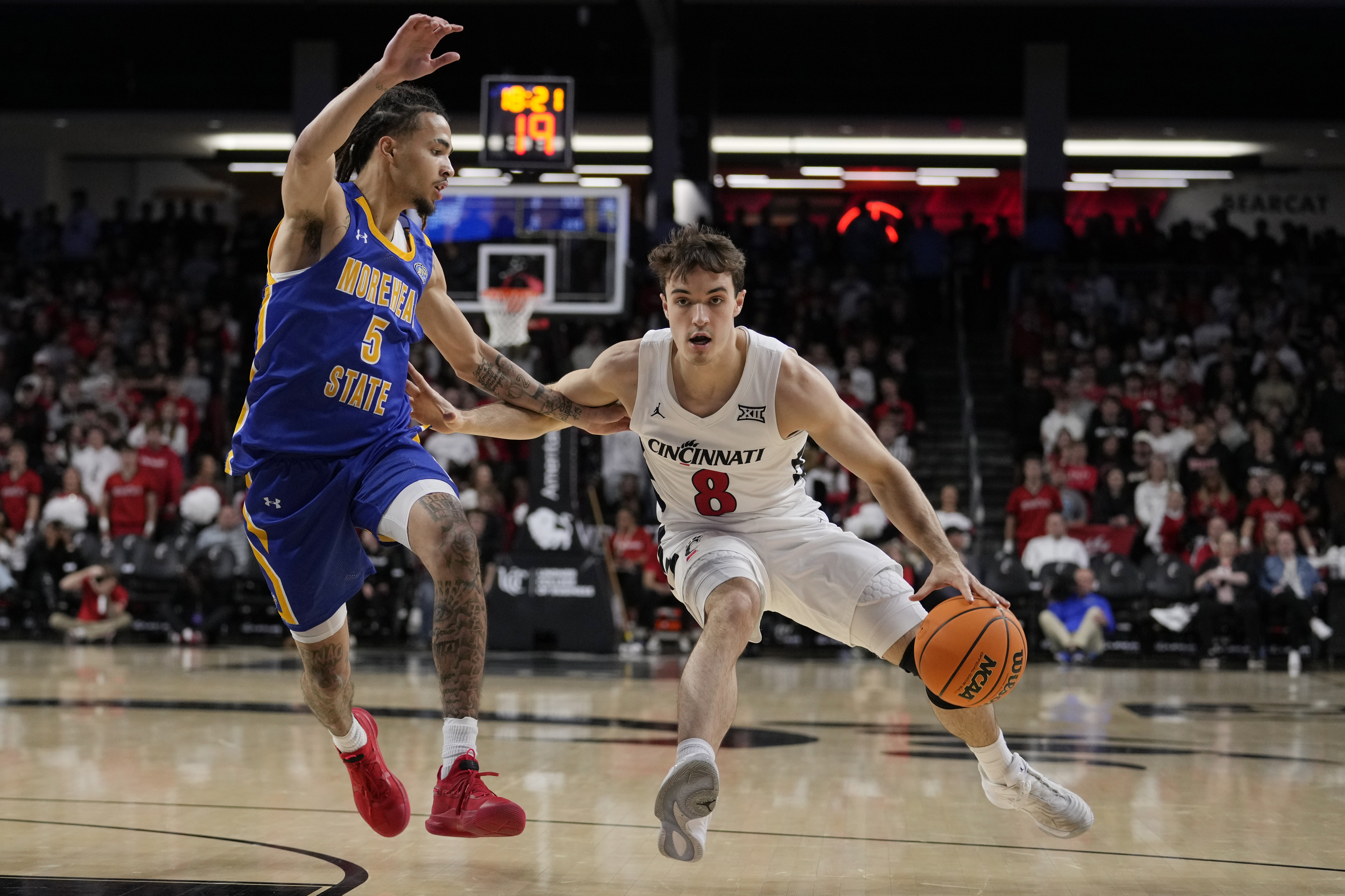 Cincinnati guard Connor Hickman (8) drives around Morehead State guard Tyler Brelsford (5) during the first half of an NCAA college basketball game, Friday, Nov. 8, 2024, in Cincinnati.