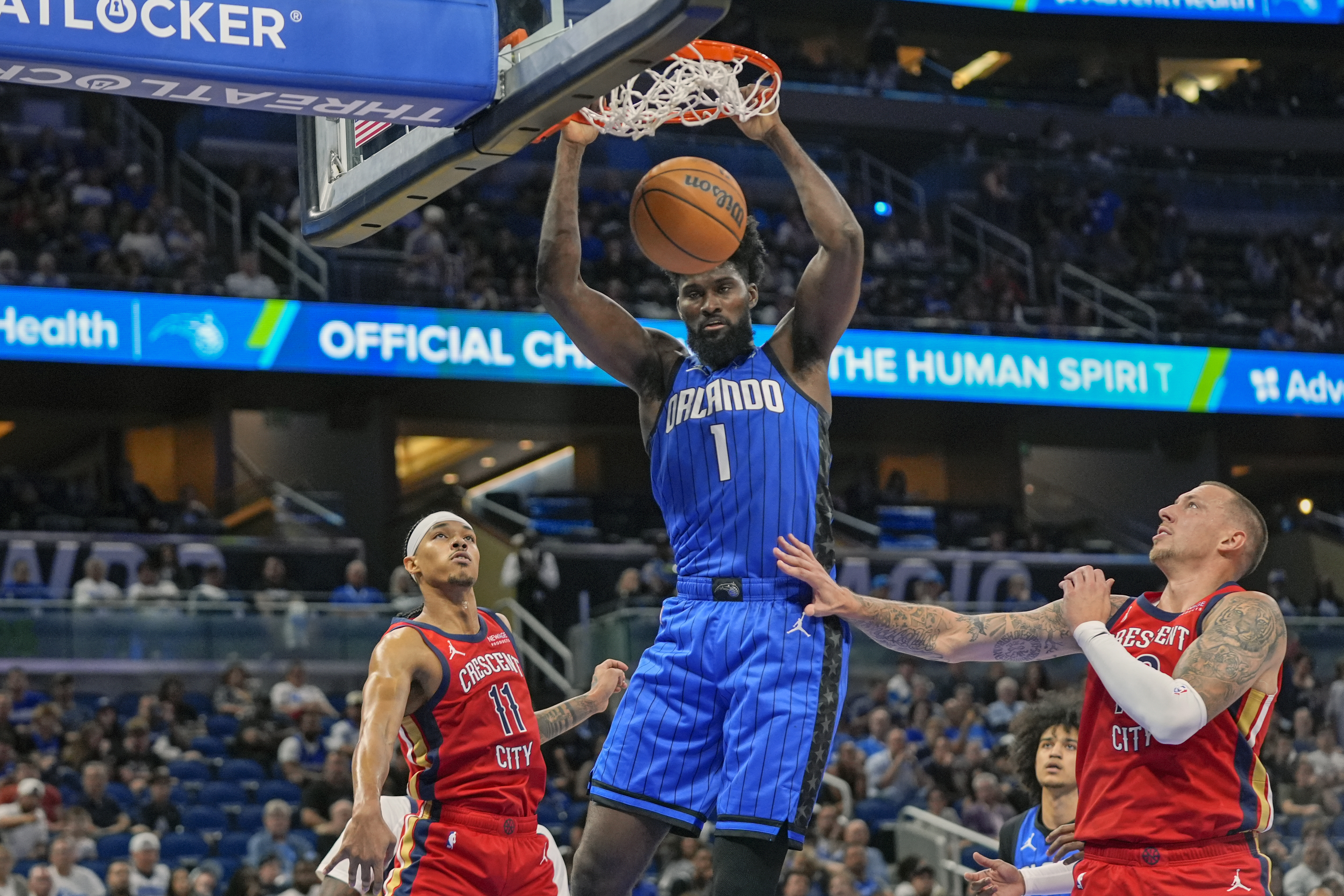 Orlando Magic forward Jonathan Isaac (1) dunks over New Orleans Pelicans guard Brandon Boston Jr. (11) and center Daniel Theis, right, during the first half of an NBA basketball game, Friday, Nov. 8, 2024, in Orlando, Fla.