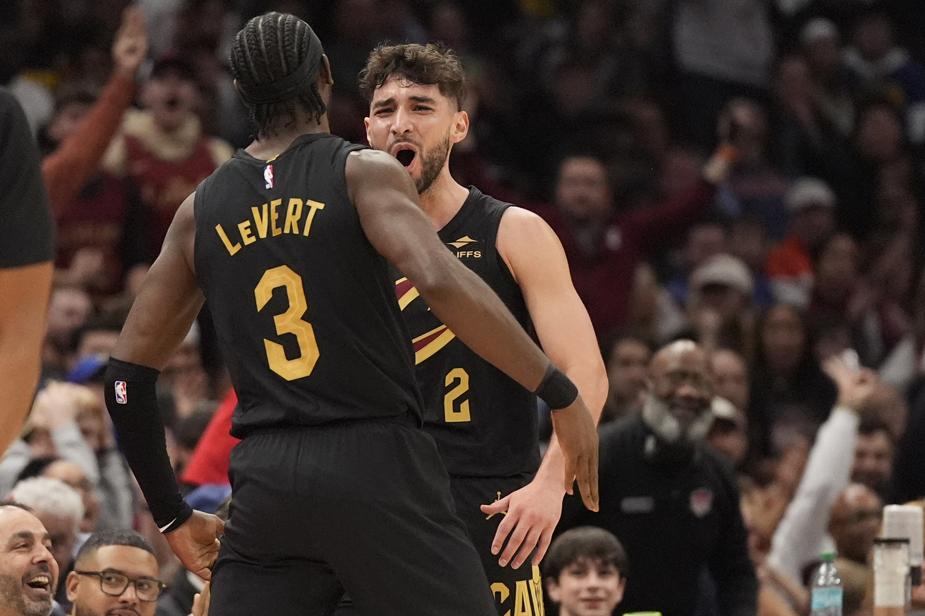 Cleveland Cavaliers guard Ty Jerome, right, celebrates a three-point basket with teammate Caris LeVert (3) in the first half of an NBA basketball game against the Golden State Warriors, Friday, Nov. 8, 2024, in Cleveland.