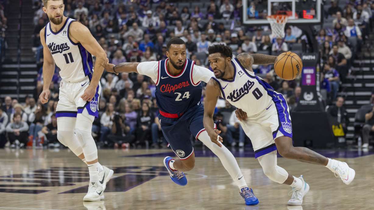 Sacramento Kings guard Malik Monk (0) dribbles around a pick set by forward Domantas Sabonis (11) on Los Angeles Clippers guard Norman Powell (24) during the first half of an NBA basketball game Friday, Nov. 8, 2024, in Sacramento, Calif.
