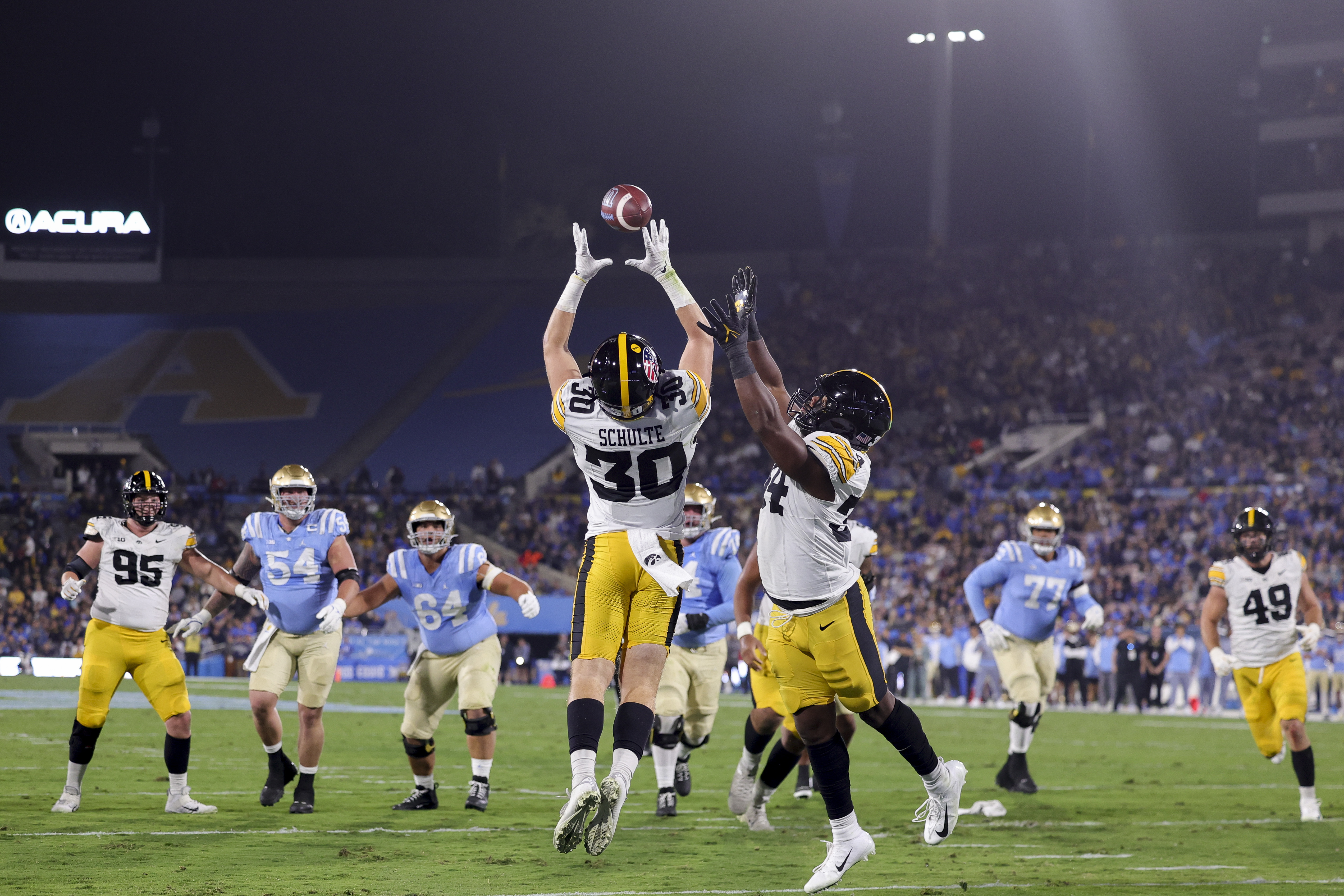 Iowa defensive back Quinn Schulte (30) jumps next to linebacker Jay Higgins (34) to intercept a pass thrown by UCLA quarterback Ethan Garbers during the first half of an NCAA college football game, Friday, Nov. 8, 2024, in Pasadena, Calif.