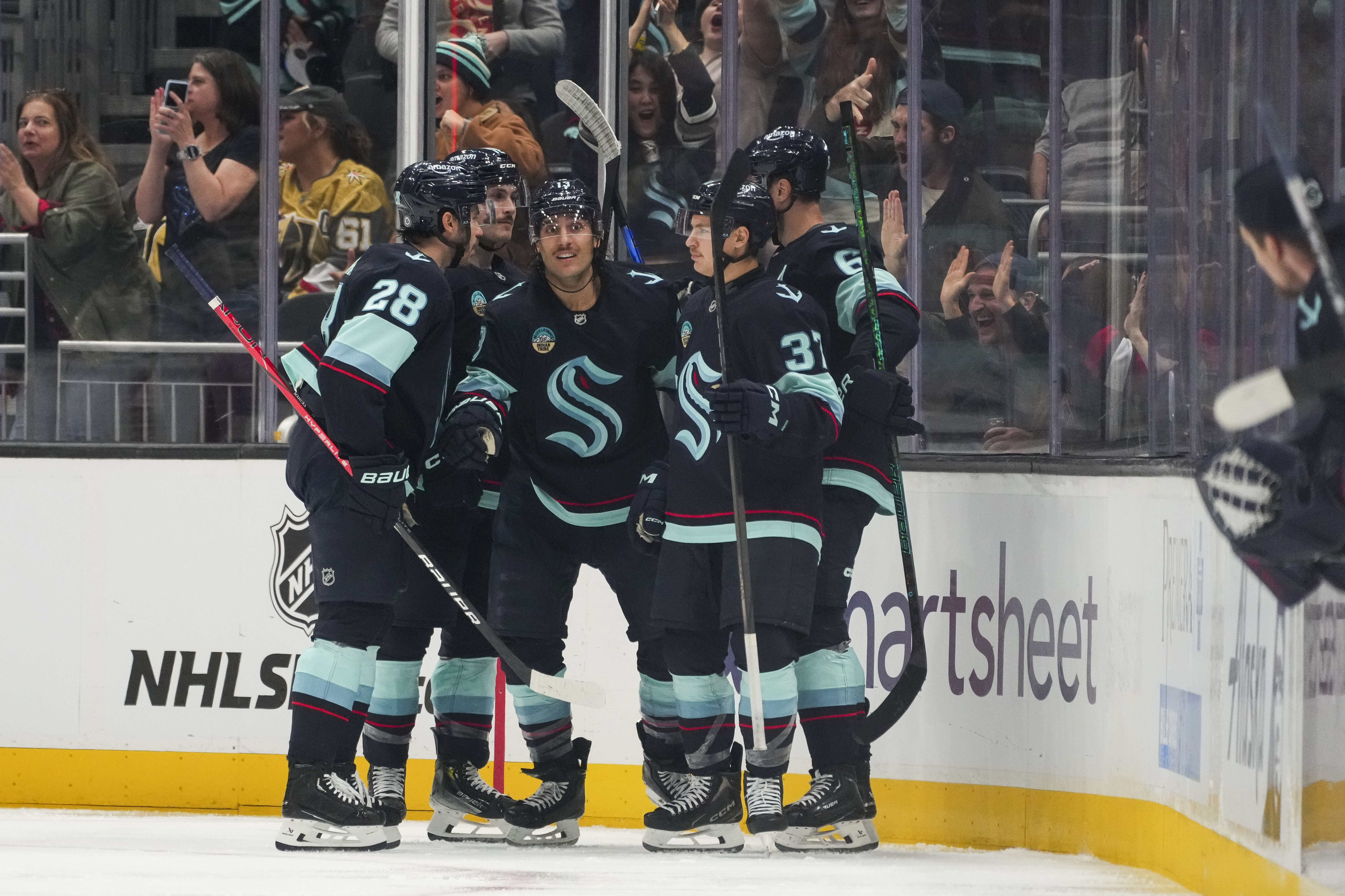 Seattle Kraken left wing Brandon Tanev, center facing, celebrates his goal against the Vegas Golden Knights with teammates, including defenseman Joshua Mahura (28) and center Yanni Gourde (37) during the second period of an NHL hockey game Friday, Nov. 8, 2024, in Seattle.