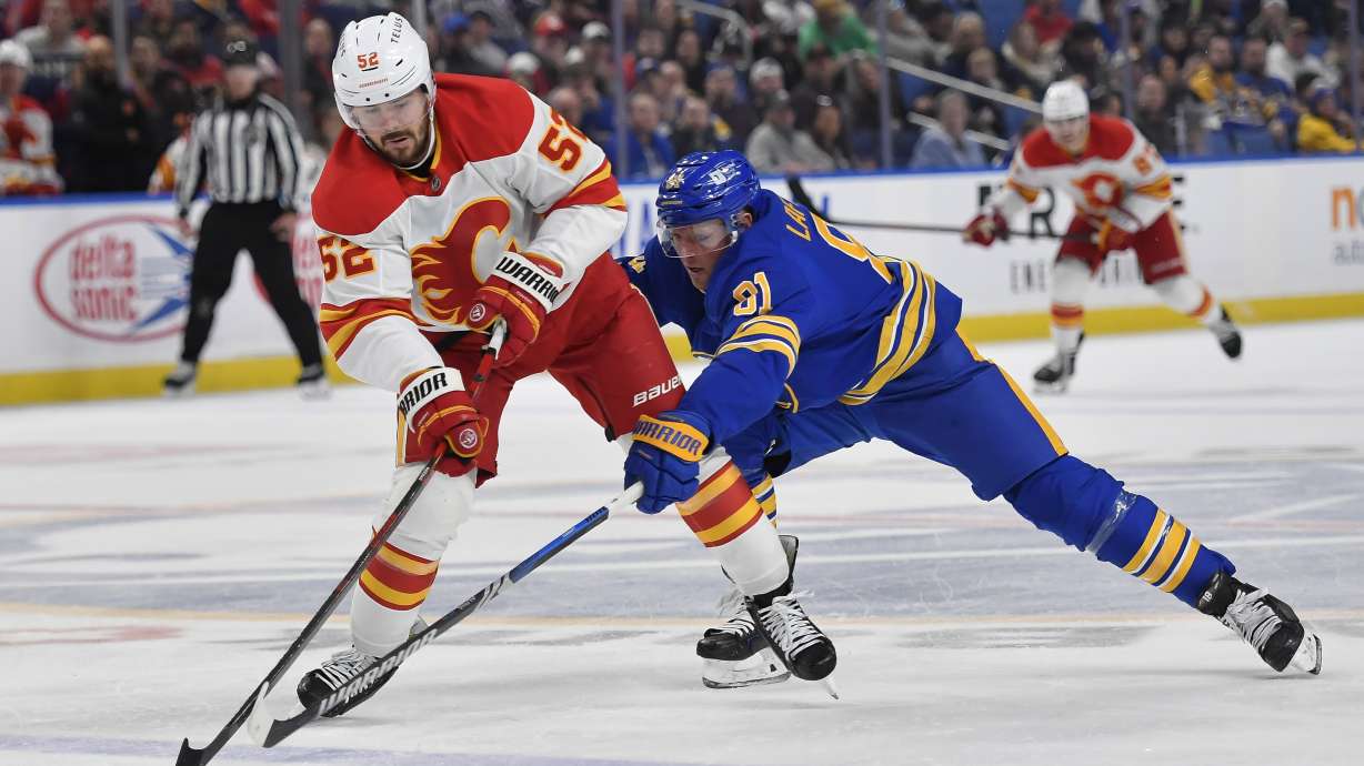 Calgary Flames defenseman MacKenzie Weegar (52) shields the puck from Buffalo Sabres center Sam Lafferty (81) during the second period of an NHL hockey game in Buffalo, N.Y., Saturday, Nov. 9, 2024.