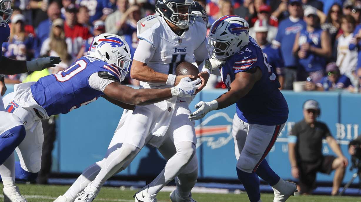 Buffalo Bills defensive end Greg Rousseau, left, and linebacker Baylon Spector (54) sack Tennessee Titans quarterback Mason Rudolph (11) during the second half of an NFL football game Sunday, Oct. 20, 2024, in Orchard Park, N.Y.