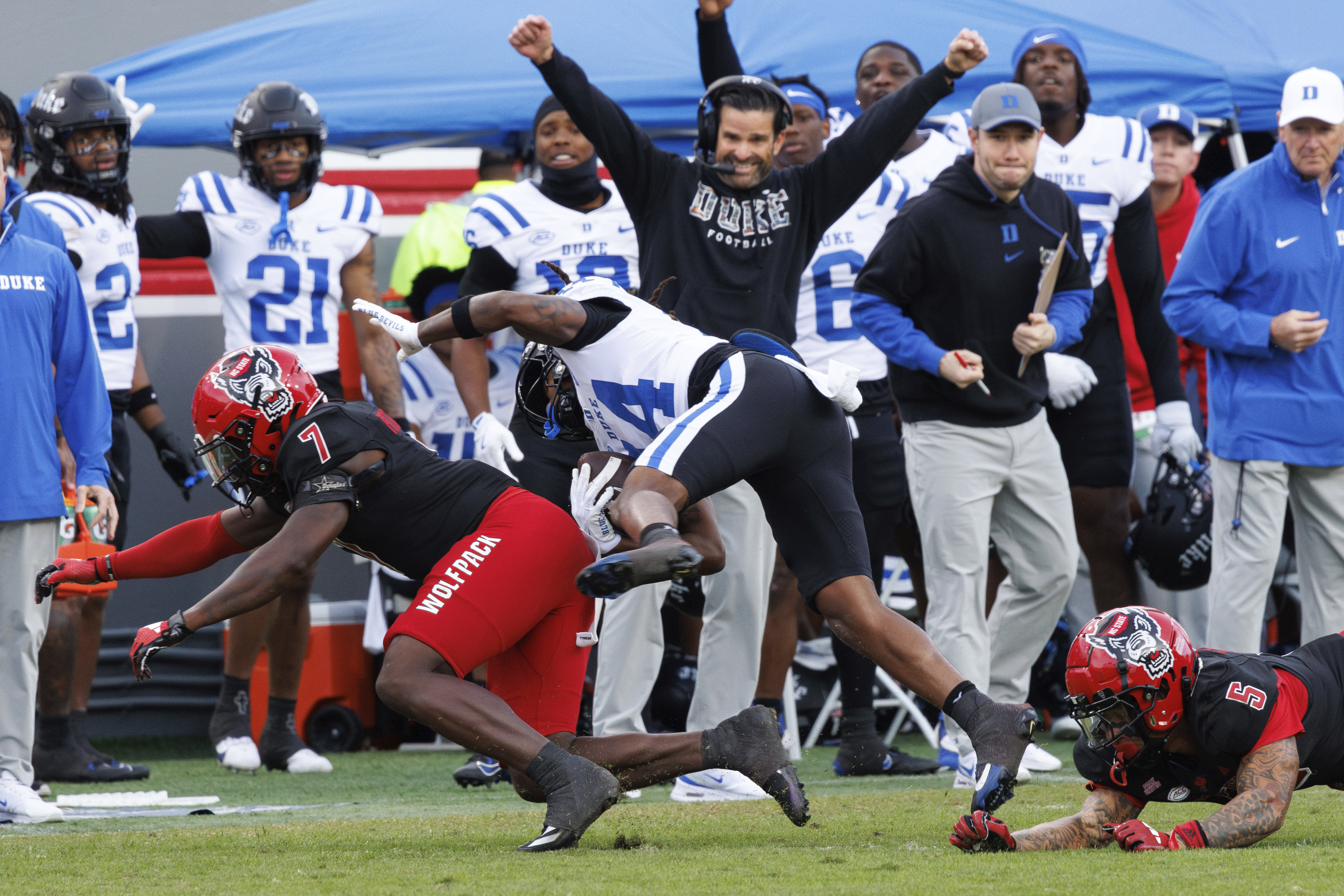 Duke's Que'Sean Brown (14) completes a catch between North Carolina State's Bishop Fitzgerald (7) and DK Kaufman (5) during the first half of an NCAA college football game in Raleigh, N.C., Saturday, Nov. 9, 2024.