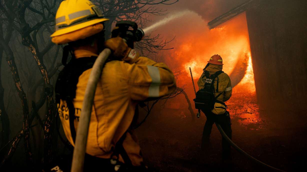 Firefighters try to control the spread of the Mountain Fire burning a structure in Camarillo, Calif., on Wednesday.